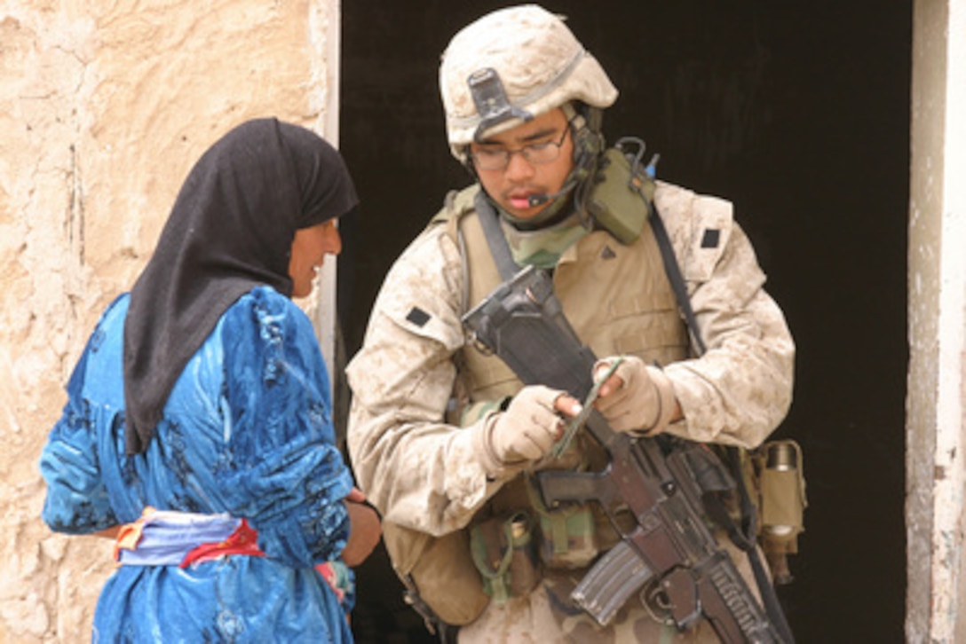 A U.S. Marine asks a woman about weapons while patrolling through a village in Fallujah, Iraq, on March 3, 2006. The Marines of 1st Squad, 3rd Platoon, 2nd Battalion, 6th Marines Regiment, Regimental Combat Team Five are conducting counter-insurgency operations with Iraqi security forces to isolate and neutralize anti-Iraqi forces. 