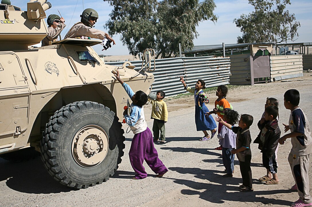 Local Iraqi children become excited as soldiers hand out candy, stuffed animals and other supplies in a village near Camp Taqaddum, Iraq, March 12th, 2006. The soldiers from 2nd Battalion, 130th Infantry Regiment, performed a multi-faceted mission during a day-long operation as they carried out weapons cache sweeps, investigated possible improvised explosive devices and conducted route clearance operations. The Illinois-based National Guard took a few moments throughout the day to assist Iraqi villagers in the area. The soldiers were grateful it wasnâ??t business as usual and could do something a little light hearted. Whether itâ??s handing out candy or searching for IEDs, the soldiers are proud of what they are doing in Iraq, said Sgt. 1st Class Timothy J. Atteberry, platoon sergeant. â??The individual, personal satisfaction of helping another human being really comes from these kinds of humanitarian-aid type missions,â? said Atteberry, a 38-year-old native of Champagne, Ill.::n::::n::The soldiersâ?? primary mission is to provide base security for the Marines and sailors of the forward-deployed 1st Marine Logistics Group. The 4,200 joint-service members of 1st MLG are part of the 25,000 Marines, airmen, solders and sailors of the 1st Marine Expeditionary Forceâ??s forward deployed element. The 1st MLGâ??s mission is to provide sustained logistics support to I MEF and Iraqi security forces operating in the Al Anbar province of Iraq. First MLG will also support the development of the Iraqi Security Forces logistic capabilities in order to enable independent ISF led counter insurgency operations.::n::