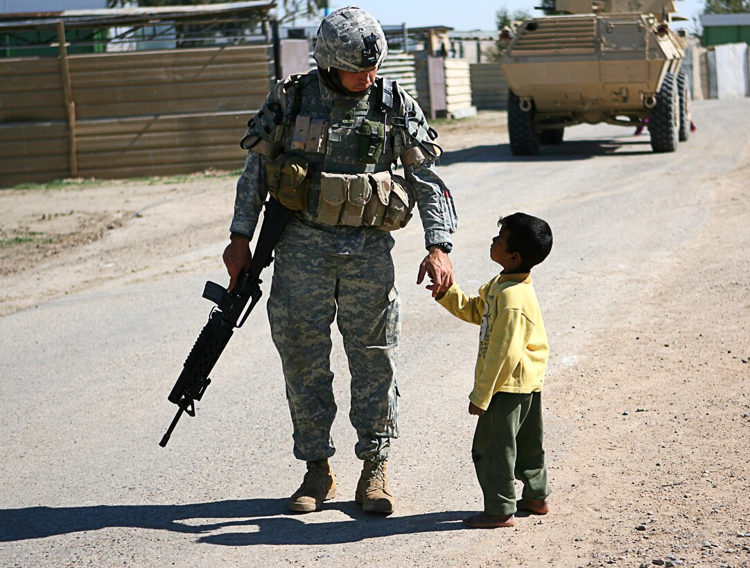 Sgt. Robert R. Anderson, infantryman, interacts with a local Iraqi child, in a village outside of Camp Taqaddum, Iraq, March 12th, 2006. Anderson, 25, a native of Gillespie, Ill., and the other soldiers from 2nd Battalion, 130th Infantry Regiment, performed a multi-faceted mission during the daylong operation as they carried out weapons cache sweeps, investigated possible improvised explosive devices and conducted route clearance operations. The Illinois-based National Guard took a few moments throughout the day to assist Iraqi villagers in the area, handing out supplies and spending time with the local children. The soldiers were grateful it wasnâ??t business as usual and could do something a little light hearted. Whether itâ??s handing out candy or searching for IEDs, the soldiers are proud of what they are doing in Iraq, said Sgt. 1st Class Timothy J. Atteberry, platoon sergeant. â??The individual, personal satisfaction of helping another human being really comes from these kinds of humanitarian-aid type missions,â? said Atteberry, a 38-year-old native of Champagne, Ill.::n::::n::The soldiersâ?? primary mission is to provide base security for the Marines and sailors of the forward-deployed 1st Marine Logistics Group. The 4,200 joint-service members of 1st MLG are part of the 25,000 Marines, airmen, solders and sailors of the 1st Marine Expeditionary Forceâ??s forward deployed element. The 1st MLGâ??s mission is to provide sustained logistics support to I MEF and Iraqi security forces operating in the Al Anbar province of Iraq. First MLG will also support the development of the Iraqi Security Forces' logistic capabilities in order to enable independent ISF led counter insurgency operations. ::n::