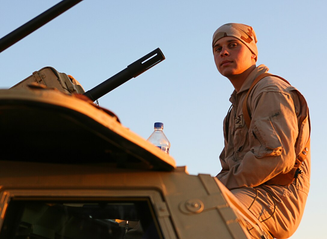 Spec. Brian R. Sterthi, infantryman, takes a moment to collect himself as he and his fellow soldiers prepare to head out on a convoy March 12, 2006, near Camp Taqaddum, Iraq. Sterthi, 21, of Lagrange, Ill., and the soldiers of 2nd Battalion, 130th Infantry Regiment, performed a multi-faceted mission during the daylong operation, as they carried out weapons cache sweeps, investigated possible improvised explosive devices and conducted route clearance operations. The Illinois-based National Guard took a few moments throughout the day to assist Iraqi villagers in the area, handing out supplies and spending time with the local children. The soldiers were grateful it wasnâ??t business as usual and could do something a little light hearted. Whether itâ??s handing out candy or searching for IEDs, the soldiers are proud of what they are doing in Iraq, said Sgt. 1st Class Timothy J. Atteberry, platoon sergeant. â??The individual, personal satisfaction of helping another human being really comes from these kinds of humanitarian-aid type missions,â? said Atteberry, a 38-year-old native of Champagne, Ill.::n::::n::The soldiersâ?? primary mission is to provide base security for the Marines and sailors of the forward-deployed 1st Marine Logistics Group. The 4,200 joint-service members of 1st MLG are part of the 25,000 Marines, airmen, solders and sailors of the 1st Marine Expeditionary Forceâ??s forward deployed element. The 1st MLGâ??s mission is to provide sustained logistics support to I MEF and Iraqi security forces operating in the Al Anbar province of Iraq. First MLG will also support the development of the Iraqi Security Forcesâ?? logistic capabilities in order to enable independent ISF led counter insurgency operations.