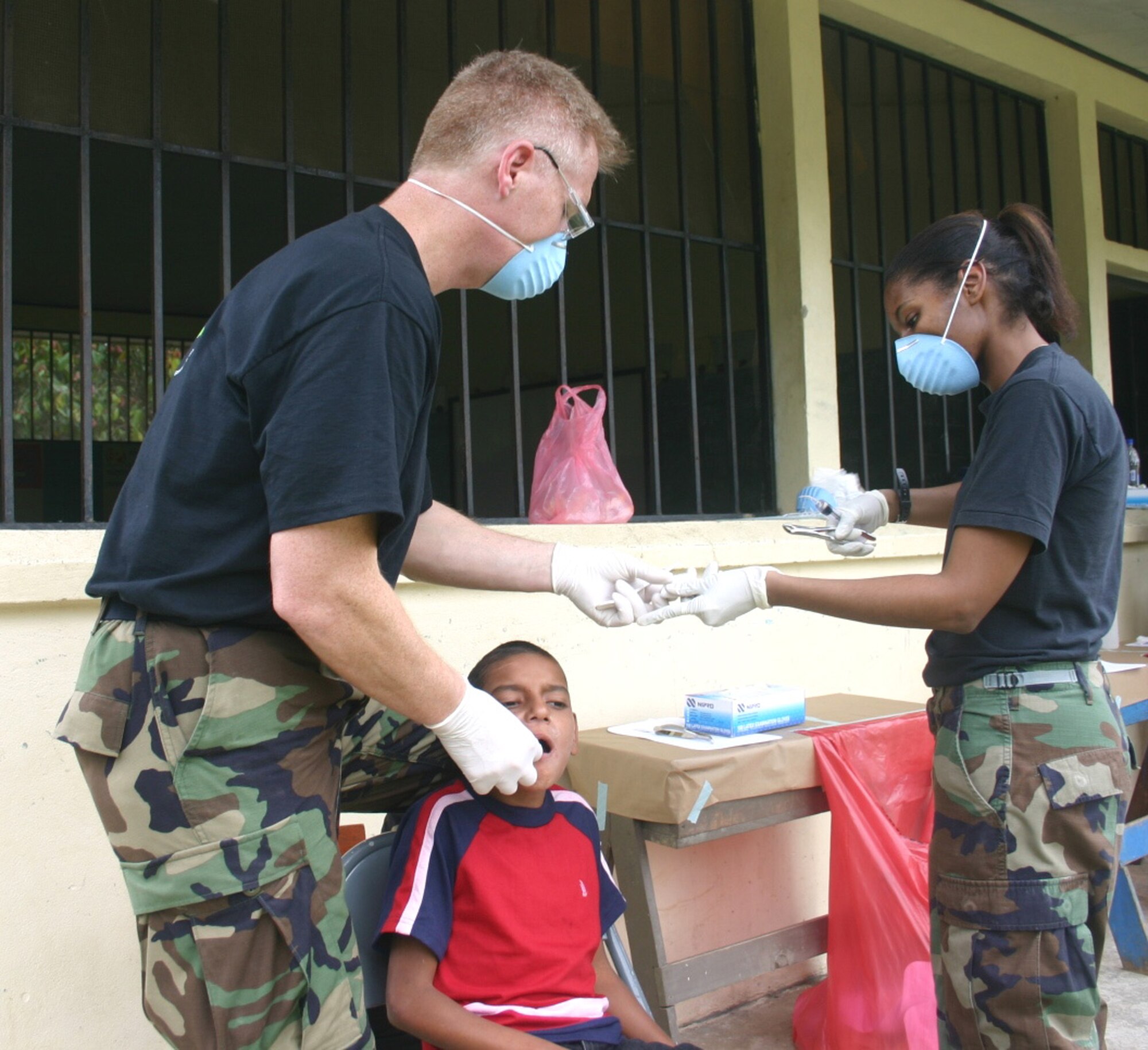 Staff Sgt. Monique Fontenot, dental technician, hands dental instruments to Lt. Col. (Dr.) Mark Means as he prepares to extract a Honduran boy's tooth. The dental team saw about 100 patients at the medical readiness training exercise site in El Recreo, Honduras. Sergeant Fontenot and Colonel Means are both deployed from the 96th Dental Squadron at Eglin Air Force Base, Fla. (U.S. Air Force photo/Capt. Mike Chillstrom)