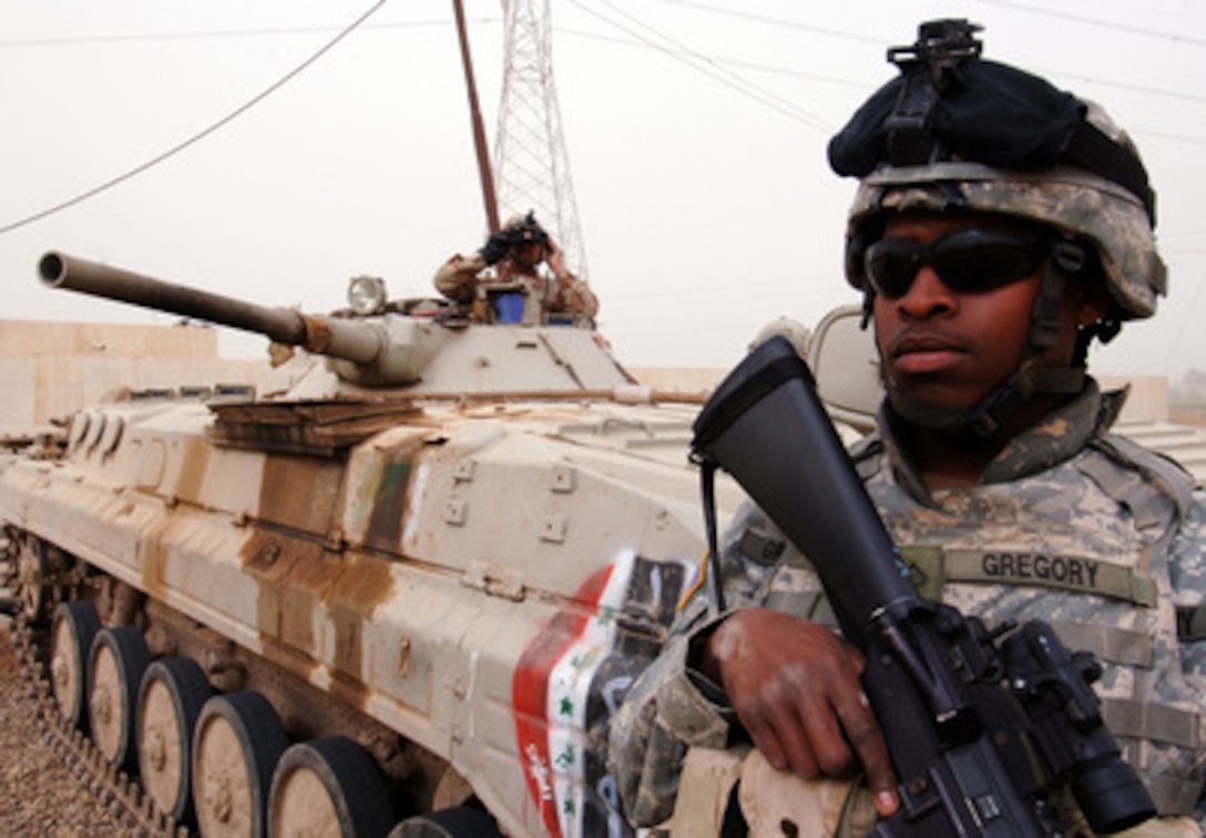 U.S. Army Pfc. Frederick Gregory maintains perimeter security as an Iraqi army soldier scans the area from his armored vehicle after an improvised explosive device attack on their convoy in Halasba, Iraq, on March 10, 2006. Gregory is assigned to the 1st Battalion, 66th Armored Regiment and the Iraqi soldier is assigned to the 9th Mechanized Division. 