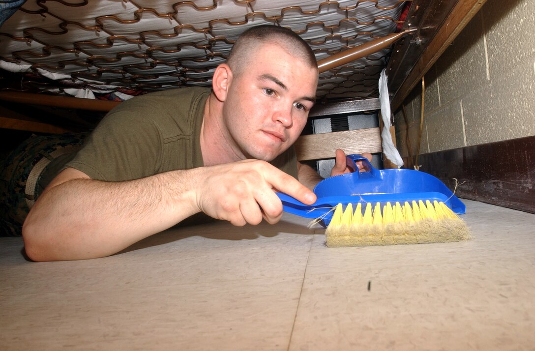 MARINE CORPS BASE CAMP LEJEUNE, N.C. - Pvt. Gary Marcum, an administration clerk with Company A, Headquarters and Support Battalion, Marine Corps Base, sweeps up dirt from under his rack in preparation for the weekly field day inspection.  Photo by:  Lance Cpl. Adam Johnston