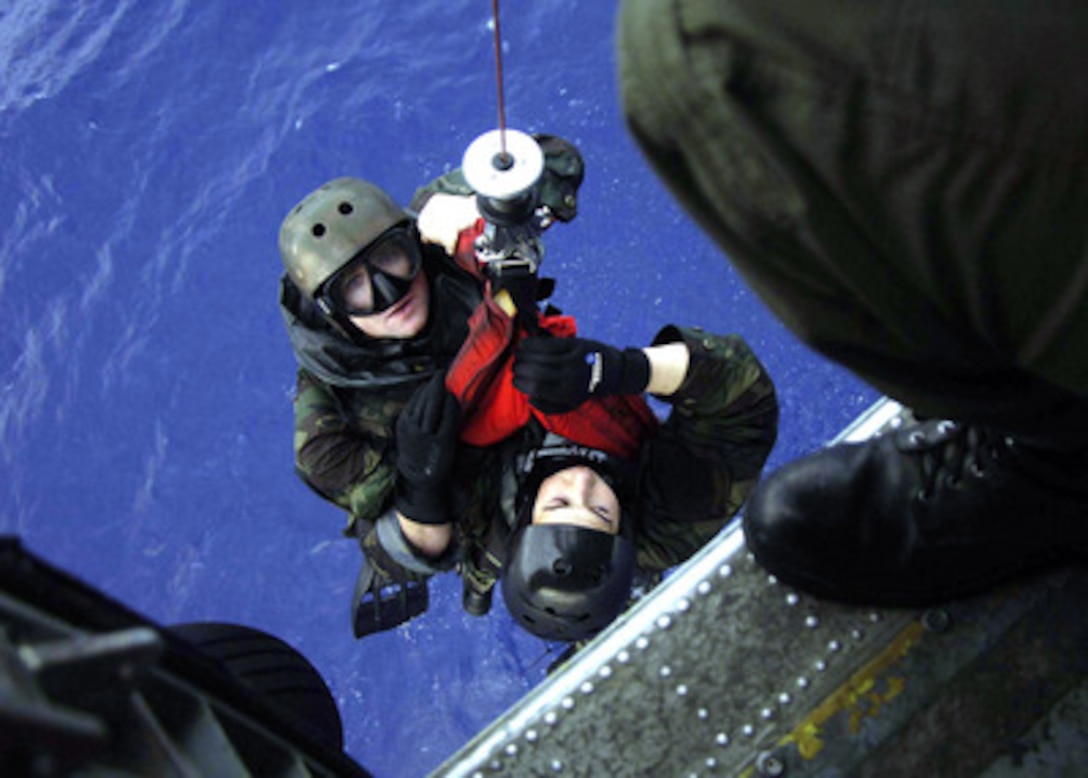 Explosive Ordnance Disposal swimmers Petty Officer 2nd Class Ryan Swanson (left) and Lt. John Laney are hoisted into an SH-60F Seahawk helicopter during casting and recovery operations in the Pacific Ocean on March 10, 2006. Swanson and Laney are attached to Explosive Ordnance Disposal Detachment 9. 