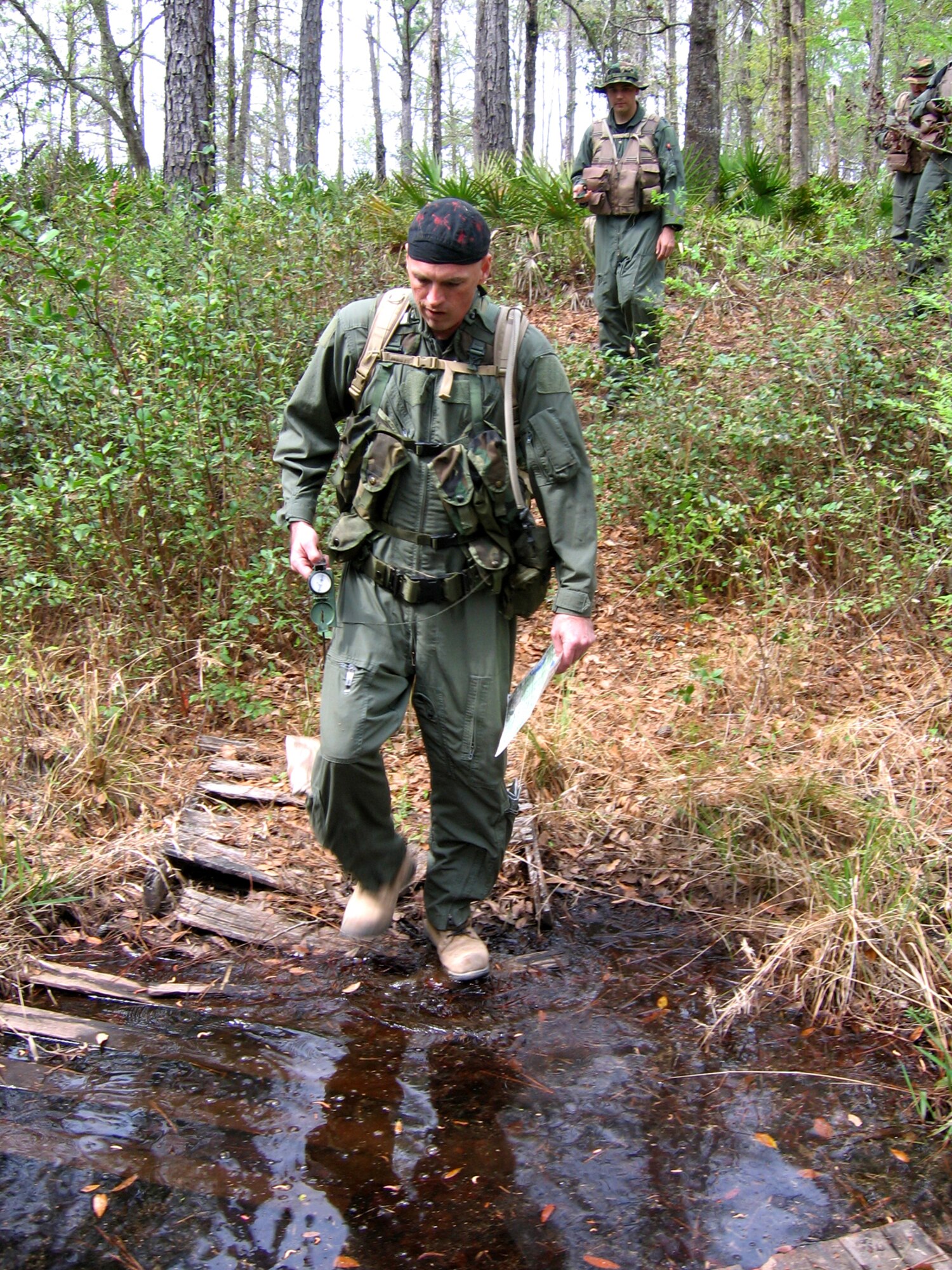 MOODY AIR FORCE BASE, Ga. - Master Sgt. John Buckler, 41st Rescue Squadron, and Capt. Joseph Booth, 347th Operations Support Squadron, cross a stream during combat survival training March 14 at Grand Bay Wildlife Management Area here. Six Moody aircrew members completed the refresher training, which teaches survival skills in combat and peacetime situations. (Photo by Airman Eric Schloeffel)