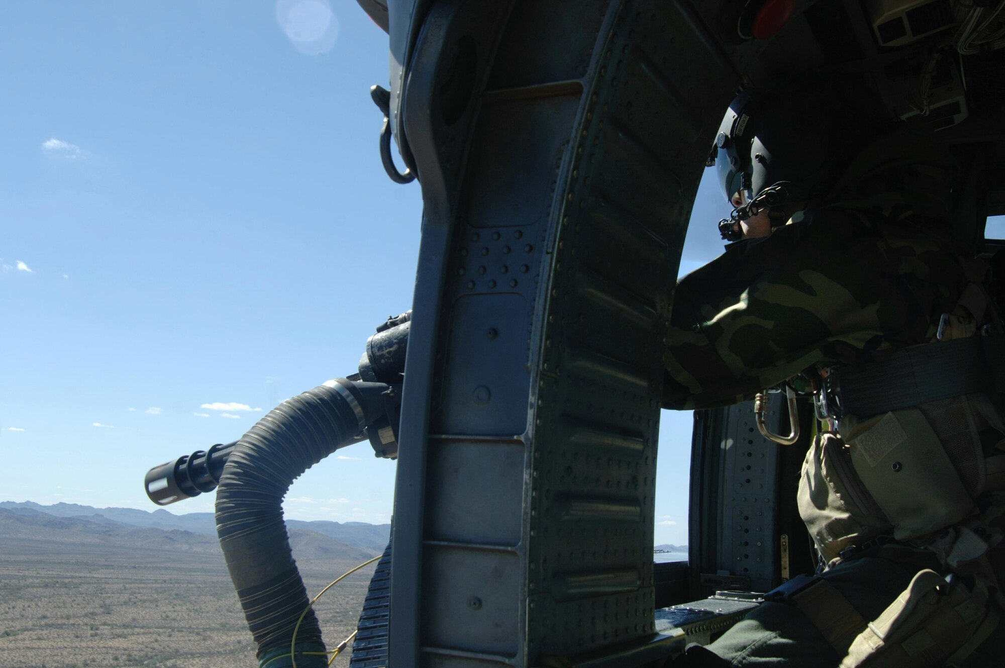 Staff Sgt Christopher Morford mans the mini gun out the side of a HH-60 Pavehawk helicopter securing the area while another HH-60 simulates rescues, Monday, March 13, 2006, at a local training area. The 55th Rescue Squadron and pararescuemen assigned to the 48th Rescue Squadron were conducting alternate insertion/extraction training near Davis-Monthan Air Force Base, Ariz.  Sergeant Morford is an aerial gunner with the 55th Rescue Squadron.   (U.S Air Force photo/Senior Airman Christina D. Ponte)
