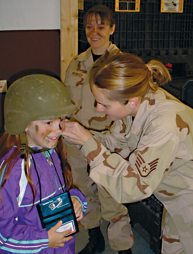 SPANGDAHLEM AIR BASE, Germany (USAFENS) -- Hannah Tuck, Bitburg Elementary School student here, gets her helmet adjusted by Staff Sgt. Suzan Alnes, 52nd Logistics Readiness Squadron readiness troop, during the junior personnel deployment function line Oct. 15. The program gives children hands-on experience of what it's like to deploy. (Photo by Sue Perron)