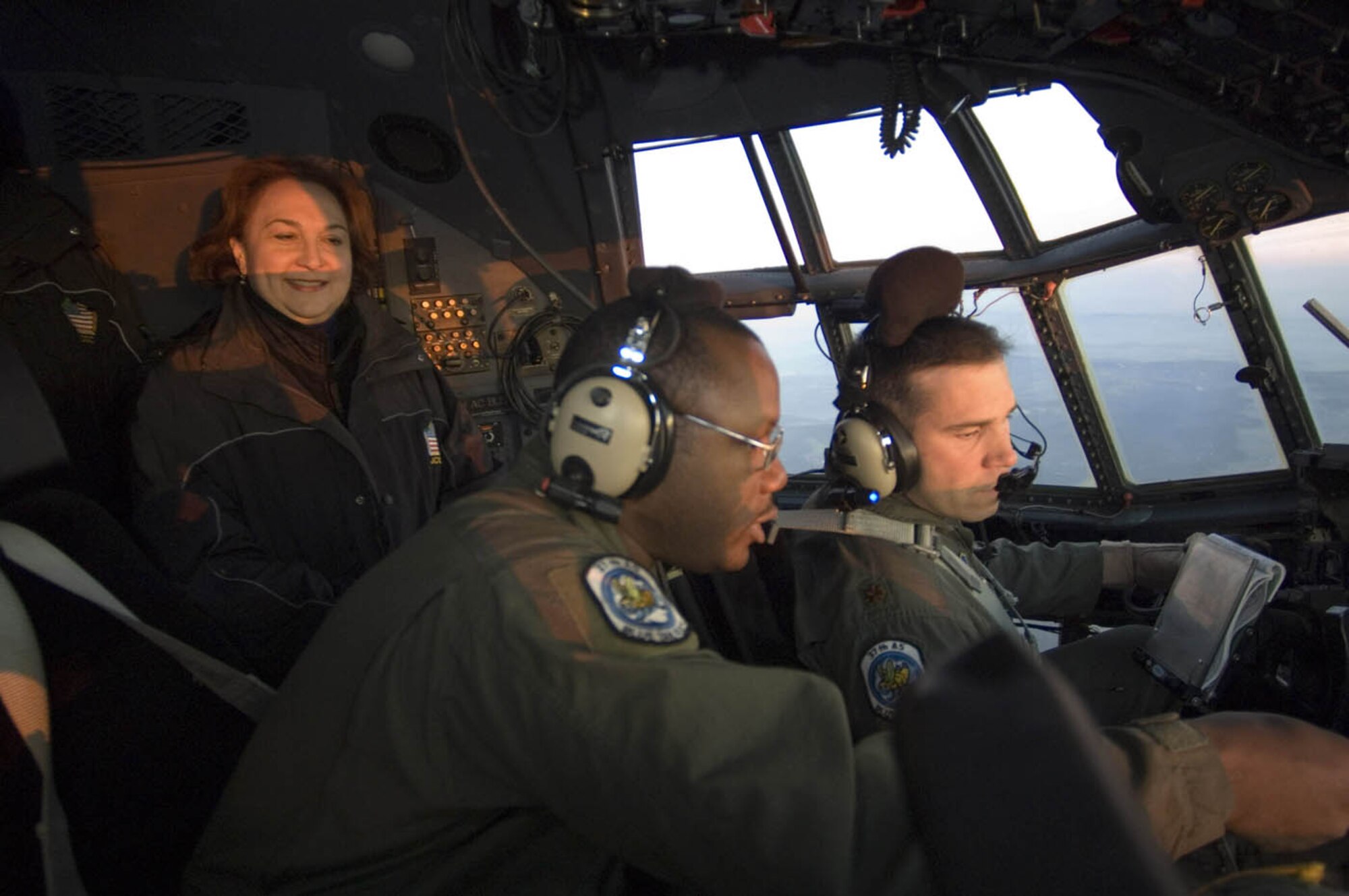 GRAFENWOER ARMY FIELD, Germany (USAFENS) -- Joint Civilian Orientation Conference participant Kathleen Mason looks on as Tech. Sgt Juan Newman (middle) and Capt. Bob Blagg, 37th Airlift Squadron, work in the C-130 Hercules cockpit. The JCOC participant’s conference is in the field with all of the Military Services observing exercises, firing weapons and participating in training. (Photo by Master Sgt. John E. Lasky)