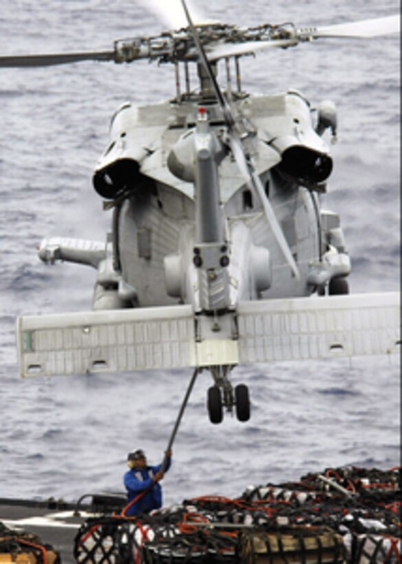 A flight deck crewman hooks up a cargo net full of supplies to a U.S. Navy SH-60F Seahawk helicopter hovering over the underway replenishment oiler USNS Pecos (T-AO 197) steaming in the Pacific Ocean on March 14, 2006. The Pecos is conducting a replenishment at sea with the aircraft carrier USS Abraham Lincoln (CVN 72). 