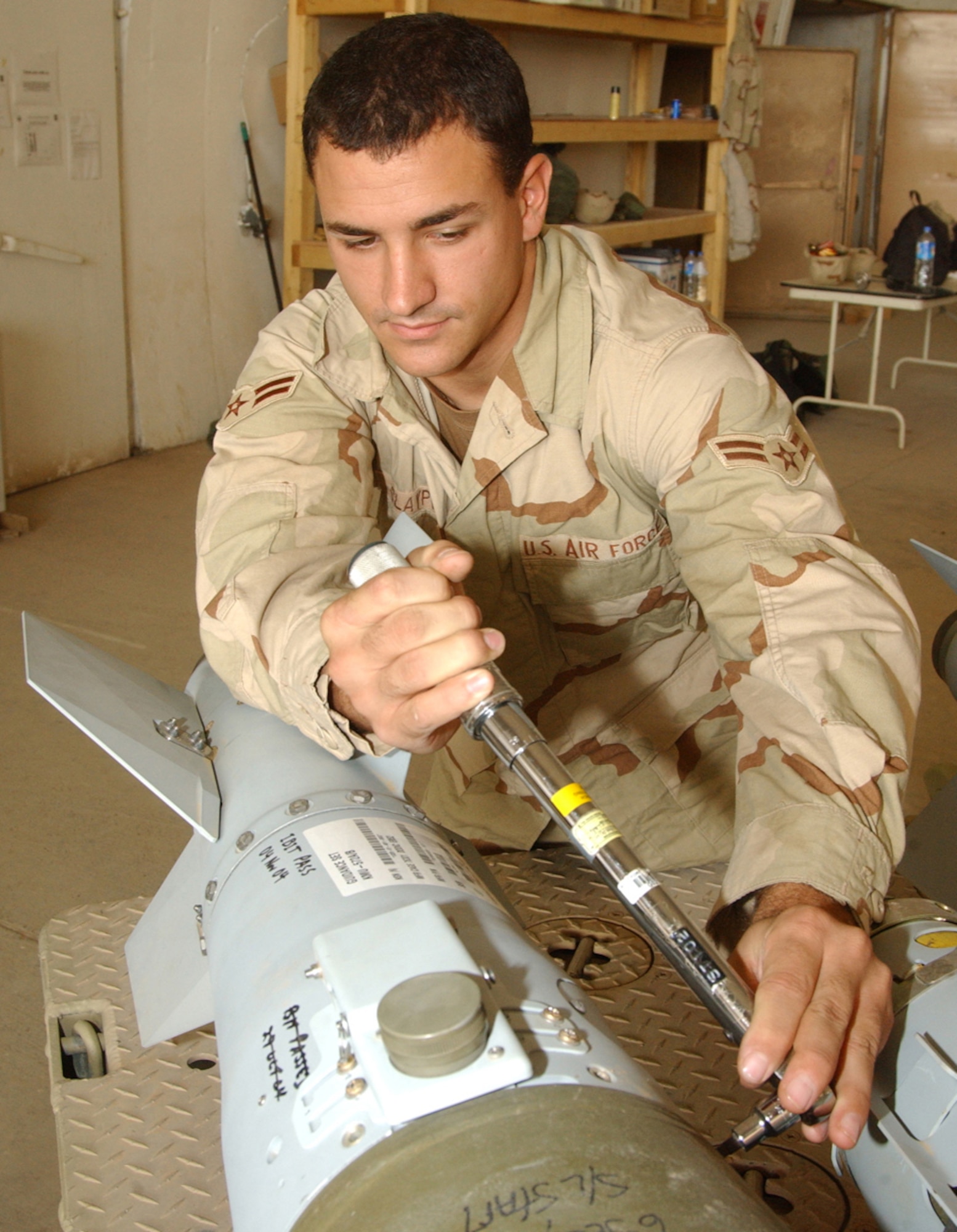Airman 1st Class Michael Claypoole, a munitions systems journeyman with the 332nd Expeditionary Maintenance Squadron, torques down the tail fin assembly of a 500-pound Joint Direct Attack Munition after it was delivered to Balad Air Base in 2004. (Air Force photo by Master Sgt. David Reagan)