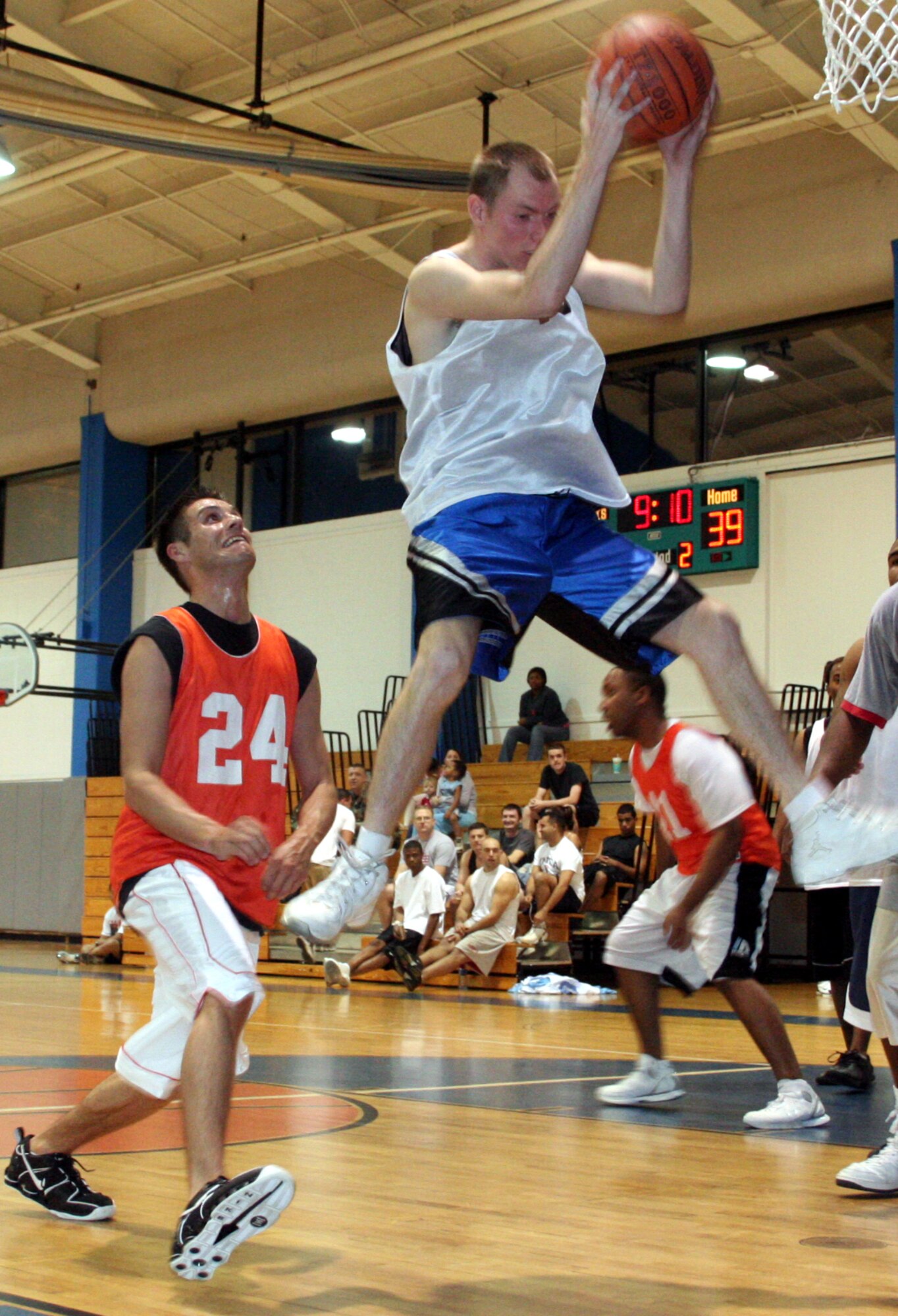 Jeff White, 16th Equipment Maintenance Squadron, rips down a defensive rebound in front of Lee Elamn, 16th Security Forces Squadron Wednesday night.  EMS won the first game of the 2006 intramural basketball playoffs with a 57-48 jailing of SFS.