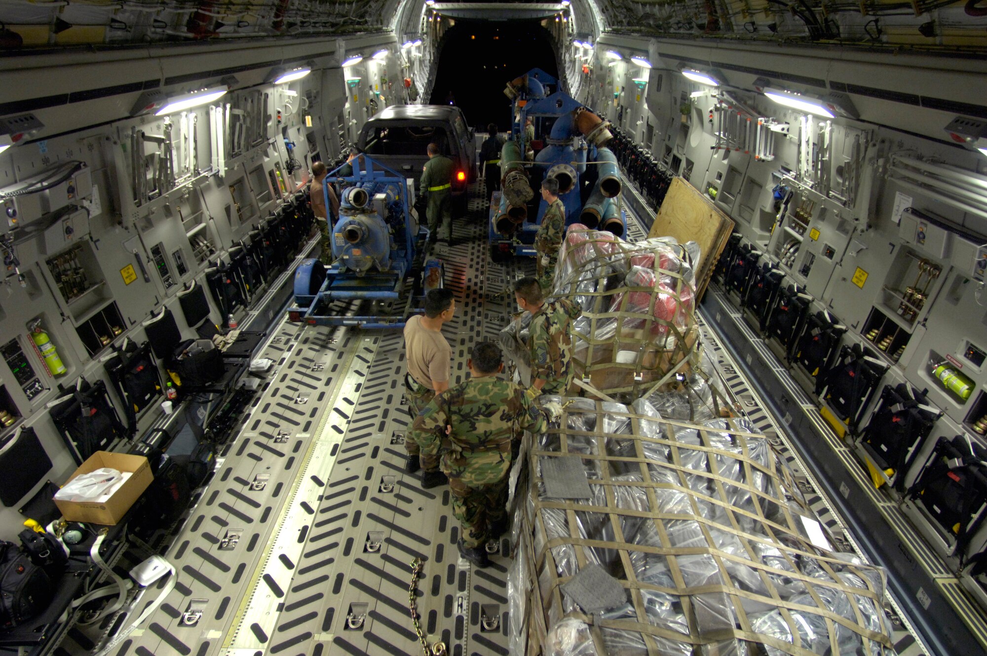 Airmen with the 291st Combat Communications Squadron and loadmasters from 204th Airlift Squadron load water pumps and recovery equipment onto a C-17 Globemaster III at Hilo International Airport, Hawaii, Thursday, March 16, 2006. The C-17 delivered recovery equipment to the island of Kauai, Hawaii, after a dam burst, isolating thousands of people along the island's north shore. (U.S. Air Force photo/Tech. Sgt. Shane A. Cuomo) 