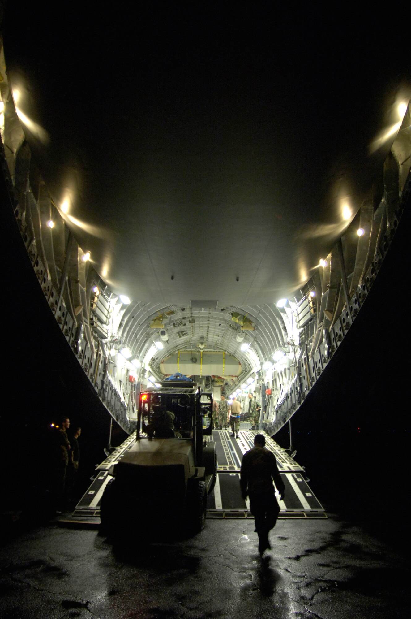 An Airman from the 291st Combat Communications Squadron uses a forklift to load a water pump onto a C-17 Globemaster III at Hilo International Airport, Hawaii, Thursday, March 16, 2006. The C-17 delivered recovery equipment to the island of Kauai, Hawaii, after a dam burst, isolating thousands of people along the island's north shore. (U.S. Air Force photo/Tech. Sgt. Shane A. Cuomo) 