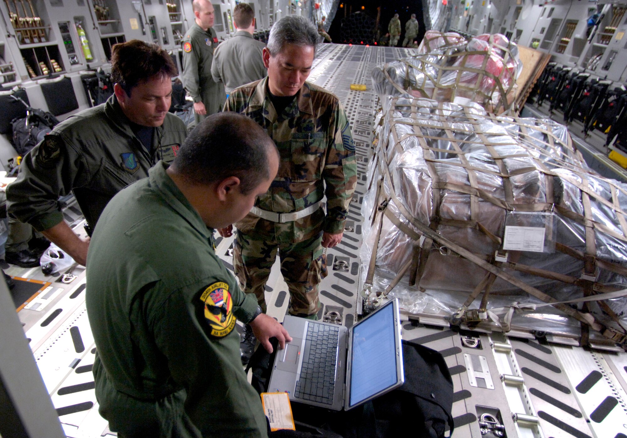 Staff Sgt. Ivan Sanches, Staff Sgt. Antonio Perry Jr. and Master Sgt. Bruce Hara look over the loading plan for a C-17 Globemaster III at Hilo International Airport, Hawaii Thursday, March 16, 2006. The C-17 delivered recovery equipment to the island of Kauai, Hawaii after a dam burst, isolating thousands of people along the island's north shore. Sergeants Sanches and Perry are with the Hawaii Air National Guard's 204th Airlift Squadron. Sergeant Hara is with the Guard's 291st Combat Communications Squadron. (U.S. Air Force photo/Tech. Sgt. Shane A. Cuomo) 