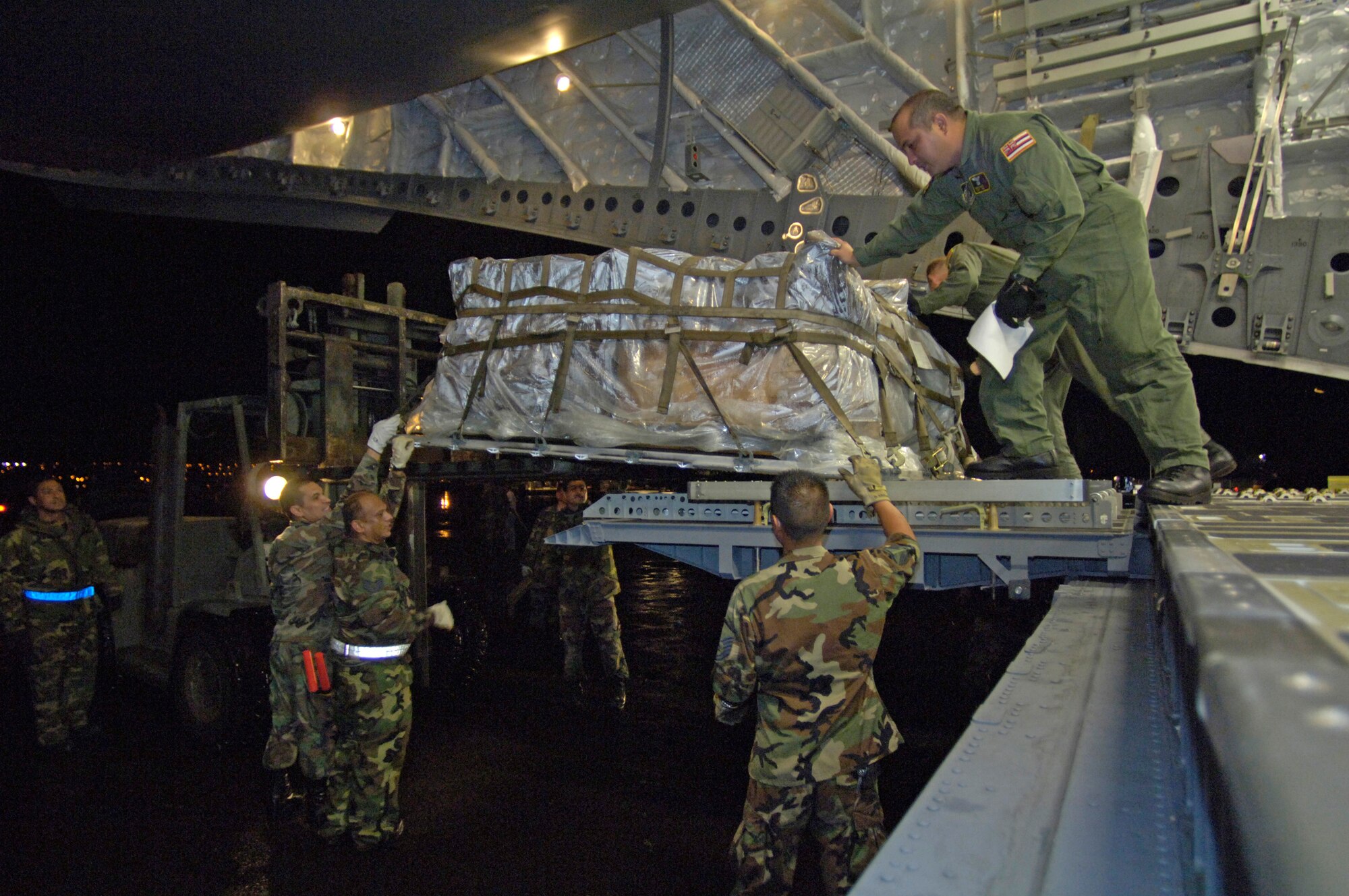 Staff Sgt. Ivan Sanches directs Airmen of the 291st Combat Communications Squadron to load recovery equipment on a C-17 Globemaster III at Hilo International Airport, Hawaii, Thursday, March 16, 2006. The C-17 delivered recovery equipment to the island of Kauai, Hawaii after a dam burst, isolating thousands of people along the island's north shore. Sergeant Sanches is with the Hawaii Air National Guard's 204th Airlift Squadron. (U.S. Air Force photo/Tech. Sgt. Shane A. Cuomo) 


