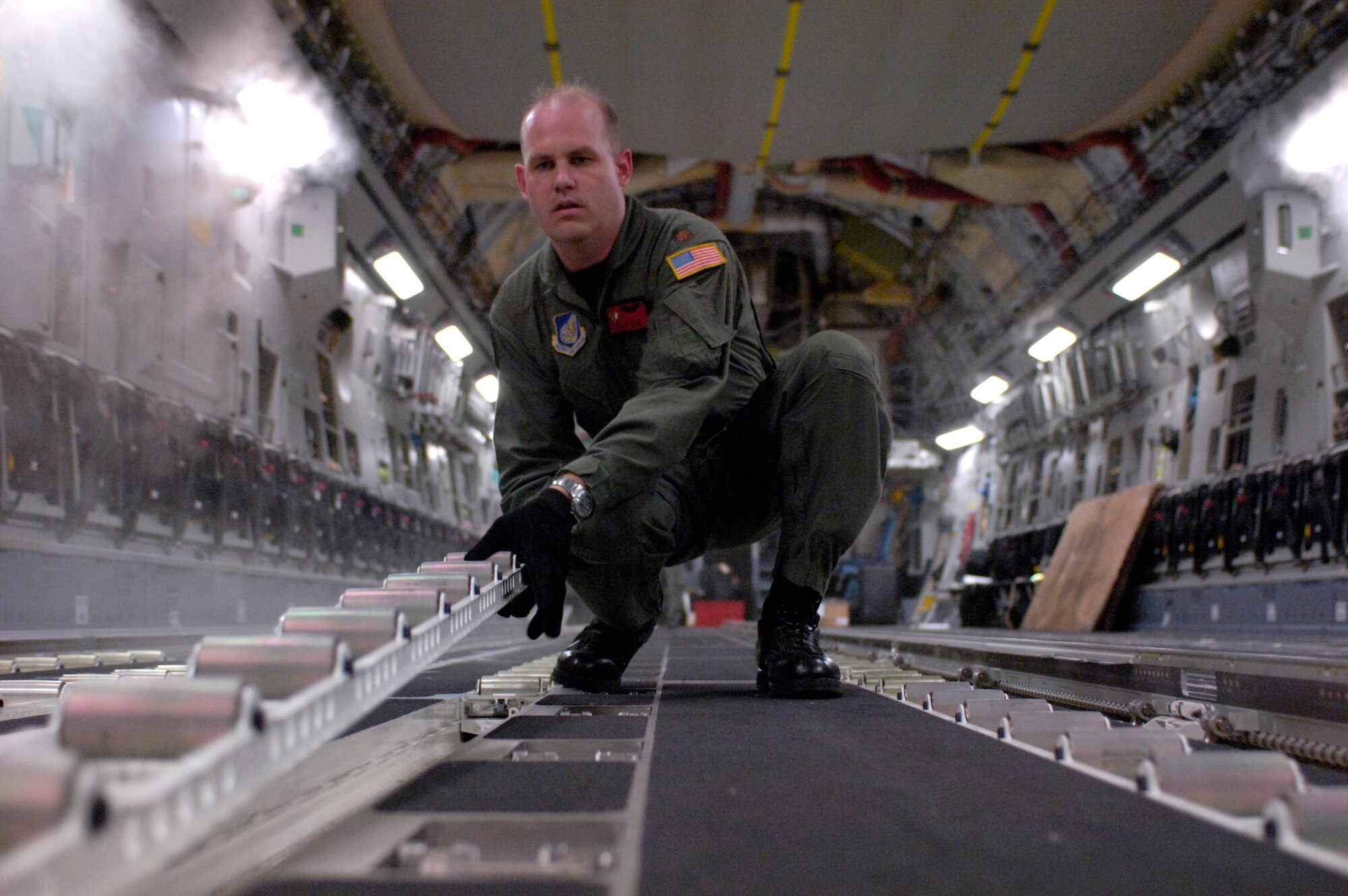 Maj. Matt Zehr turns over rollers to configure a C-17 Globemaster III for loading at Hilo International Airport, Hawaii Thursday, March 16, 2006. The C-17 delivered recovery equipment to the island of Kauai, Hawaii, after a dam burst, isolating thousands of people along the island's north shore. Major Zehr is with the 535th Airlift Squadron at Hickam Air Force Base, Hawaii. (U.S. Air Force photo/Tech. Sgt. Shane A. Cuomo) 