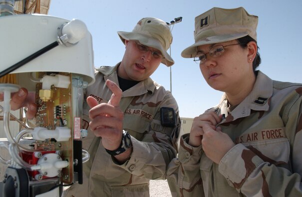 Senior Airman Chad Frost and Capt. Lara Henry take readings and adjust a minivol portable air sampler at a deployed location in Southwest Asia. The two work with the 379th Expeditionary Medical Group's bioengineering flight to monitor and collect samples of particulate matter. The information will be used to determine potential short- and long-term health effects of personnel deployed in the region.  (U.S. Air Force photo/Airman 1st Class Anthony Nelson Jr.)
