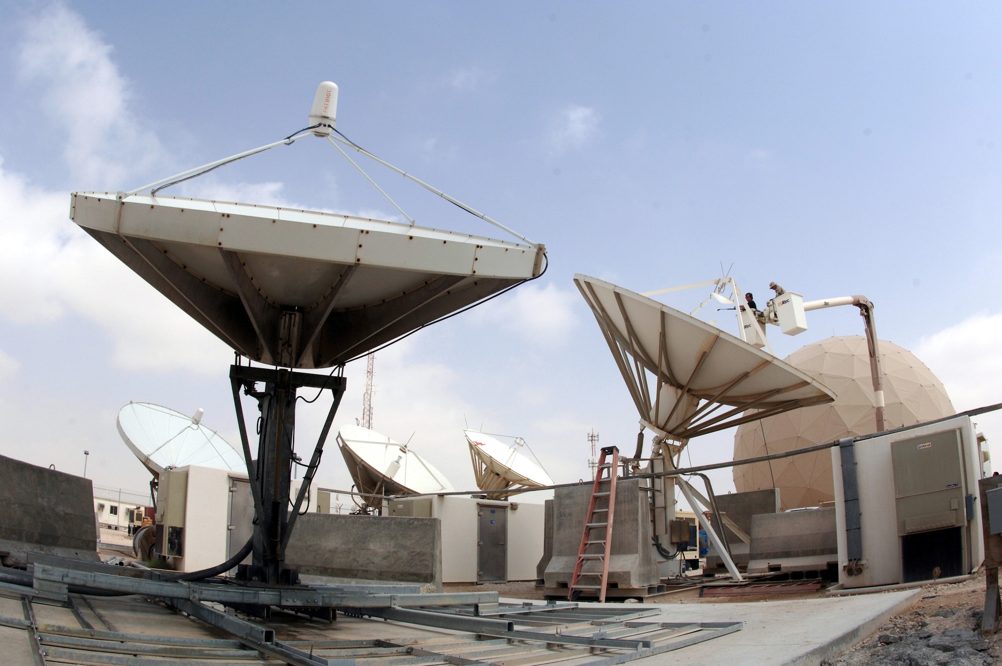 Matt Rogers power-washes satellite dishes at a deployed location in Southwest Asia on Sunday, March 19, 2006, with a lift from the 379th Expeditionary Civil Engineer Squadron. The satellites provide communication capabilities to forward-deployed units. Mr. Rogers is a civilian contractor. (U.S. Air Force photo/Staff Sgt. Joshua Strang)