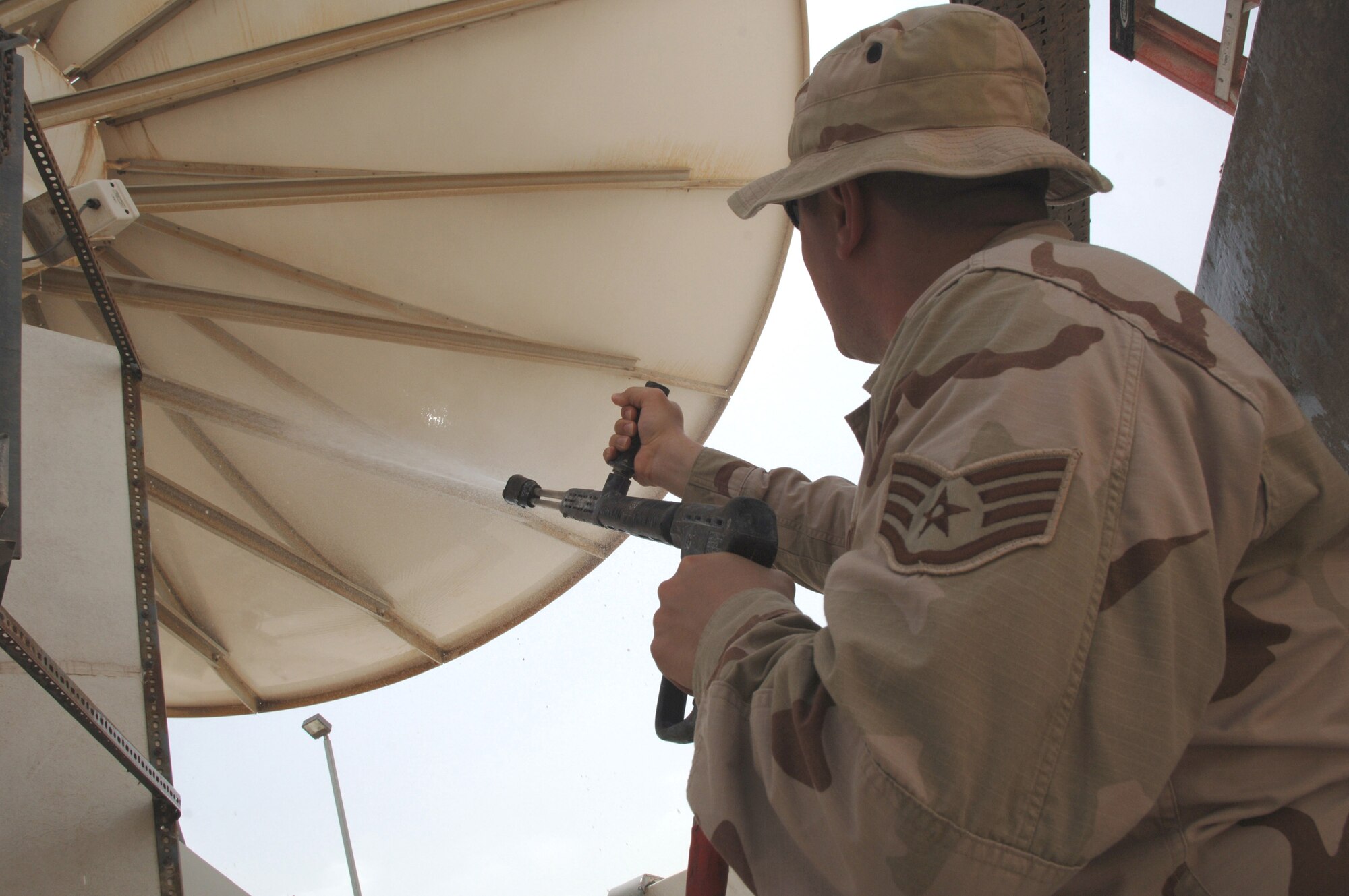 Staff Sgt. Michael Droddy power-washes satellite dishes at a deployed location in Southwest Asia on Sunday, March 19, 2006. The satellites provide communication capabilities to forward-deployed units. Sergeant Droddy is with the 379th Expeditionary Communications Squadron. (U.S. Air Force photo/Staff Sgt. Joshua Strang)
