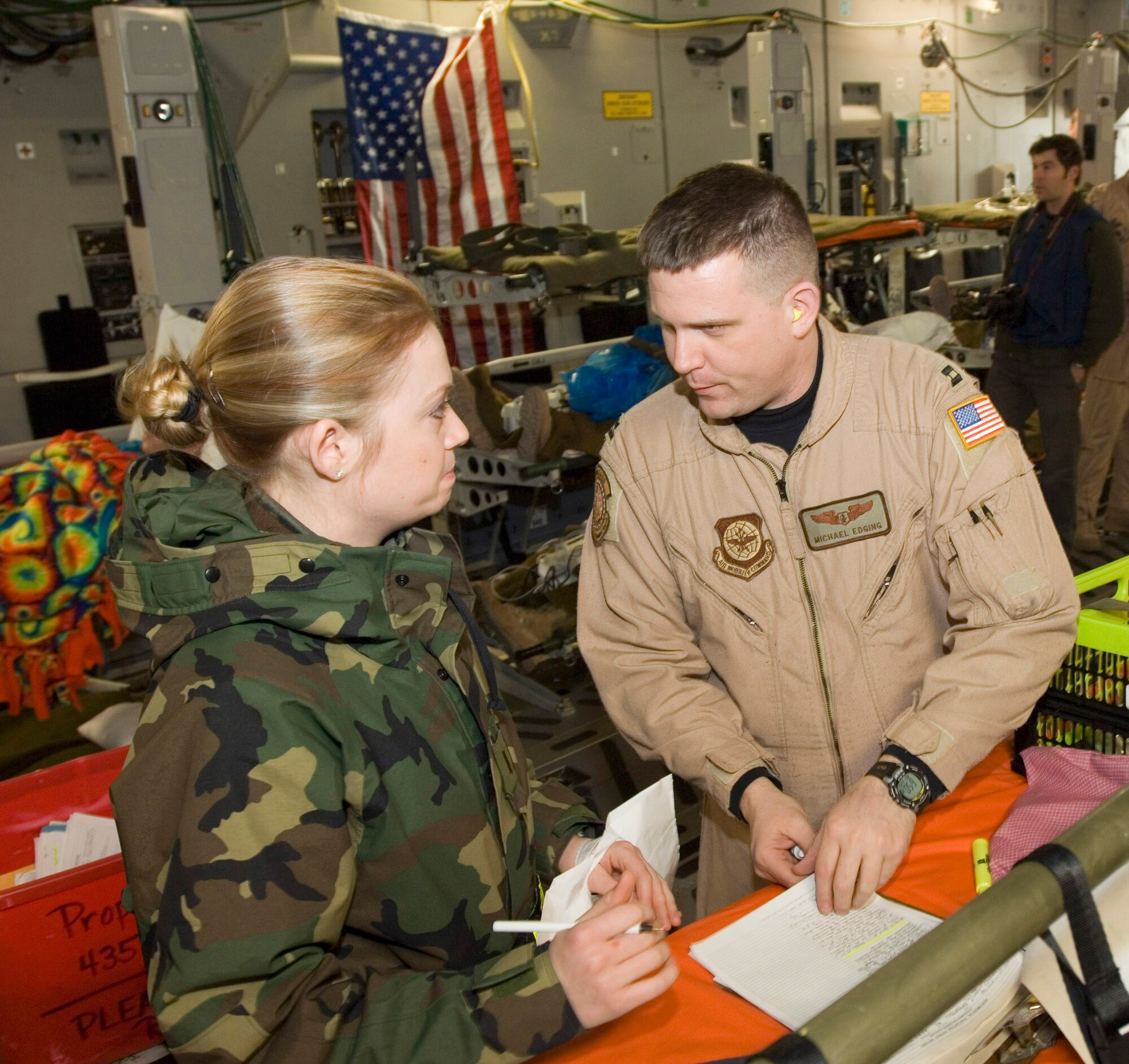 Second Lt. Dana Erickson, left, and Capt. Michael Edging exchange patient information on a C-17 Globemaster III at Ramstein Air Base, Germany, on Monday, March 20, 2006. The aircraft flew a routine mission to deliver cargo to Al Asad, Iraq, and picked up patients at Balad Air Base, Iraq, for the return flight. The Mississippi Air National Guard transport surpassed the transport fleet's 1 millionth hour of flight milestone. Lieutenant Erickson is on temporary duty at Ramstein's 435th Contingency Aeromedical Staging Facility. Captain Edging is on temporary duty with Ramstein's 791st Expeditionary Aeromedical Evacuation Squadron. (U.S. Air Force photo/Master Sgt. John E. Lasky) 