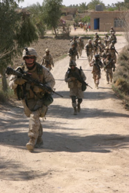U.S. Marines and Iraqi army soldiers advance up a dirt road as they search for weapons caches and materials used to make improvised explosive devices during a patrol along the Euphrates River in Fallujah, Iraq, on March 17, 2006. Marines from 3rd Squad, 2nd Platoon, Echo Company, 2nd Battalion, 6th Marine Regiment, Regimental Combat Team 5 and Iraqi soldiers are from the 2nd Battalion, 4th Brigade, 1st Division are conducting the joint patrol. 