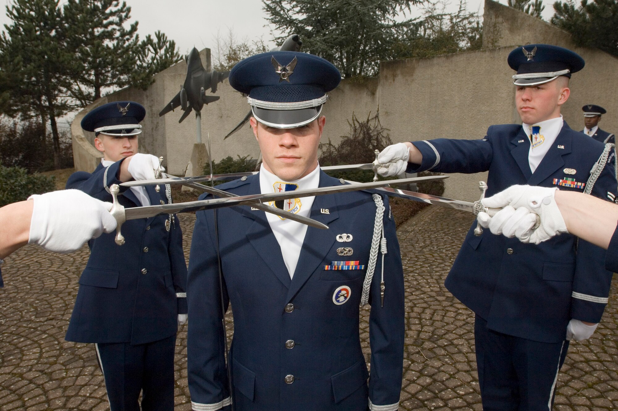 First Lt. Brian Cooper stands in the middle of fellow Sabre Drill Team members Airmen 1st Class Dallas Smith and Jacob McCarty, left and right, respectively, at a practice session at Spangdahlem Air Base, Germany, on Tuesday, March 21, 2006. Lieutenant Cooper is a maintenance flight commander for the 52nd Equipment Maintenance Squadron. Airman Smith is a computer networking cryptographic switching system journeyman with the 606th Air Control Squadron. Airman McCarty is a quality assurance evaluator with the 52nd Civil Engineer Squadron. (U.S. Air Force photo/Master Sgt. John E. Lasky) 