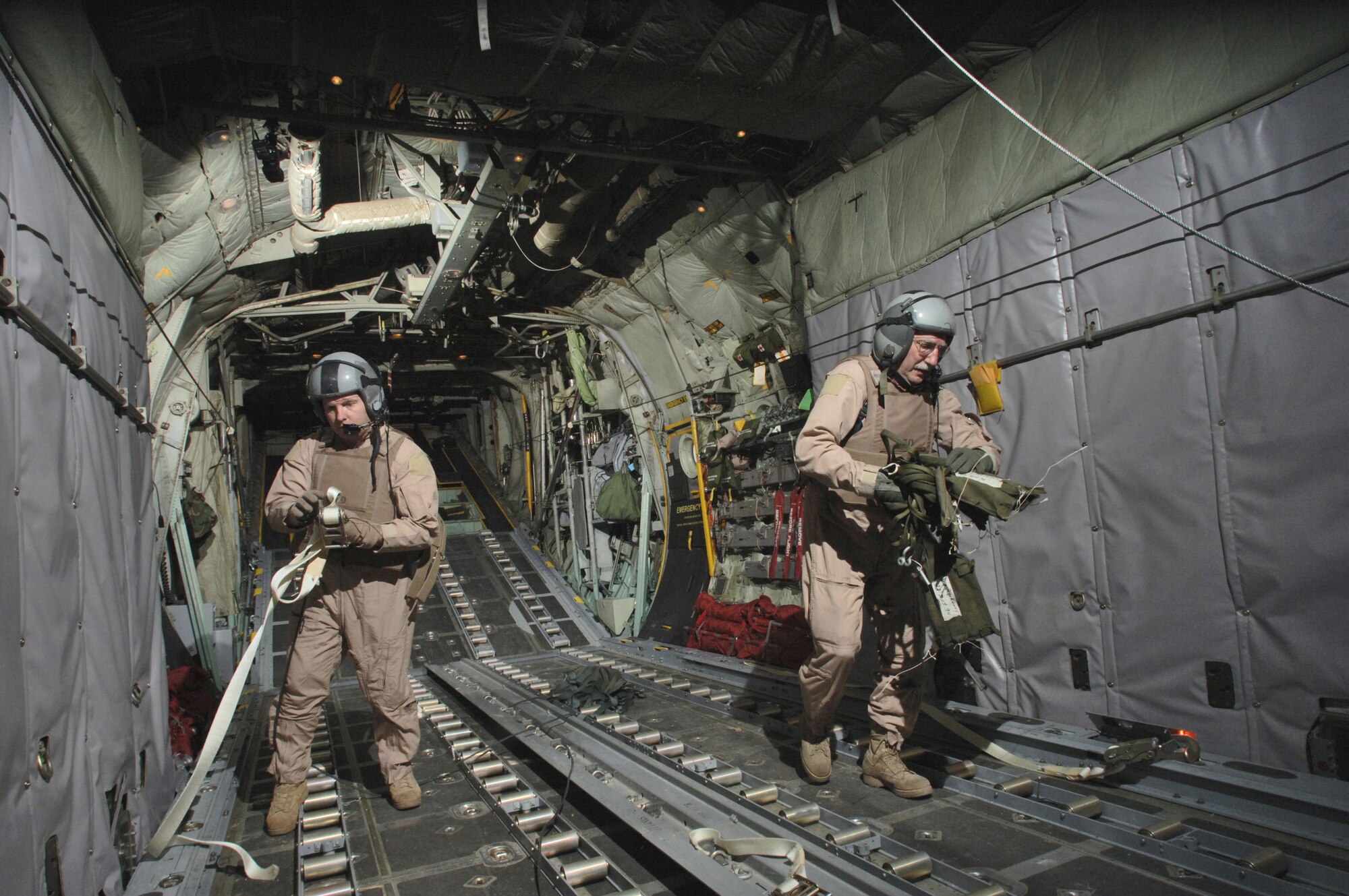 Senior Master Sgt. Ted Poplarchik (right) and Master Sgt. Bruce Leehan clean up used rigging during their flight back to their deployed base Thursday, March 9, 2006.  Their crew just delivered 24,000 pounds of material to three different forward operating bases miles from the Pakistan border. Sergeant Poplarchik is with 144th Airlift Squadron, Kulis Air National Guard Base, Alaska, and Sergeant Leehan is with Oklahoma Air National Guard's 185th Airlift Squadron at Will Rogers World Airport.  Both are deployed to the 774th Expeditionary Airlift Squadron at Bagram Air Base, Afghanistan. (U.S. Air Force photo/Master Sgt. Lance Cheung)