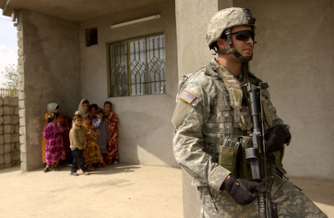 Iraqi children watch U.S. Army Cpl. Jesse Bay as he and his fellow soldiers conduct a house search during a patrol in Mosul, Iraq, on March 19, 2006. Bay is attached to the 2nd Battalion, 1st Infantry Regiment, 172nd Infantry Brigade. 