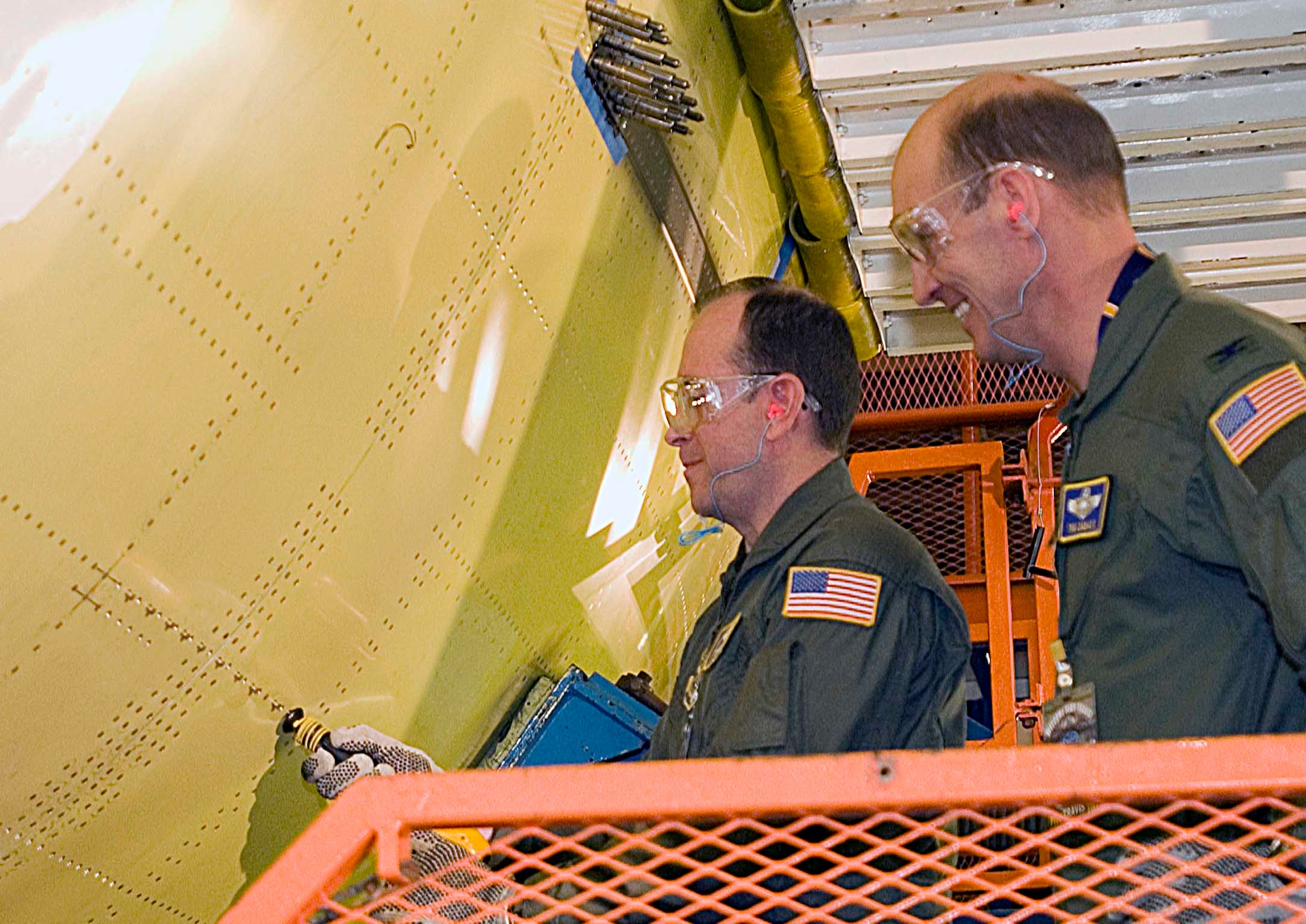 Col. Timothy Zadalis, 60th Air Mobility Wing vice commander [right], watches Brig. Gen. Thomas Gisler Jr., 349th AMW commander, drill a rivet into the first C-17 Globemaster III scheduled to arrive at Travis in the end of July. (U.S. Air Force photo by David Cushman)