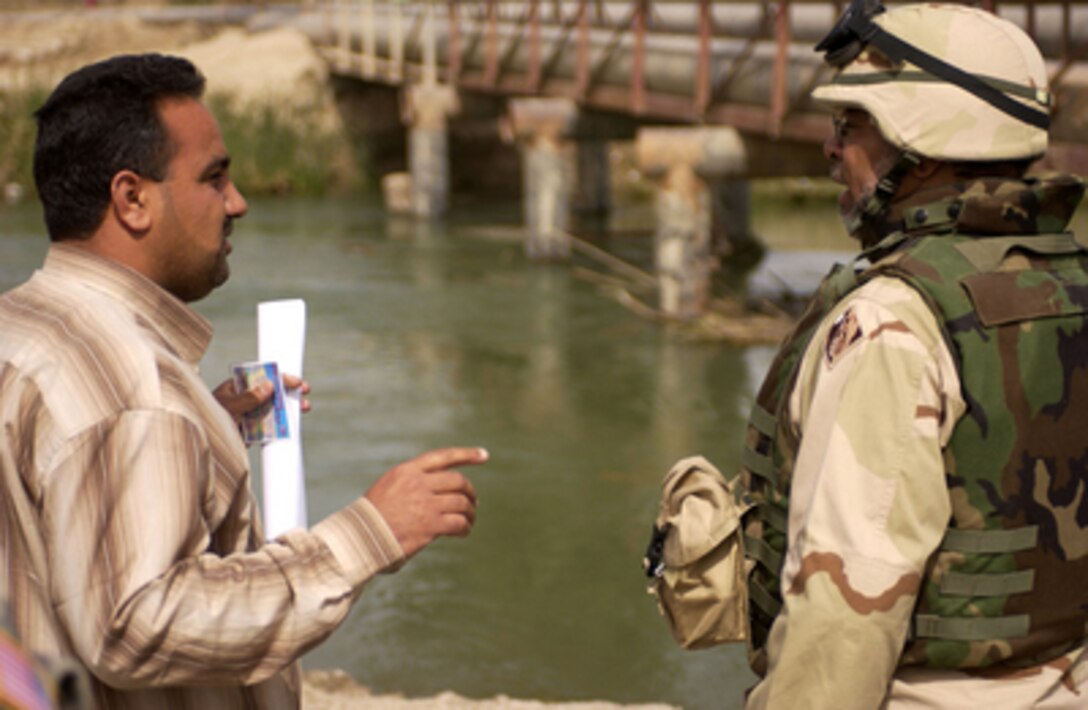 Alsace Dyer, an engineer with the U.S. Army Corps of Engineers, Multinational Division - Central South, speaks with an Iraqi contractor as they do a site survey of the Hamza Bridge in Diwaniyah, Iraq, on March 22, 2006. 