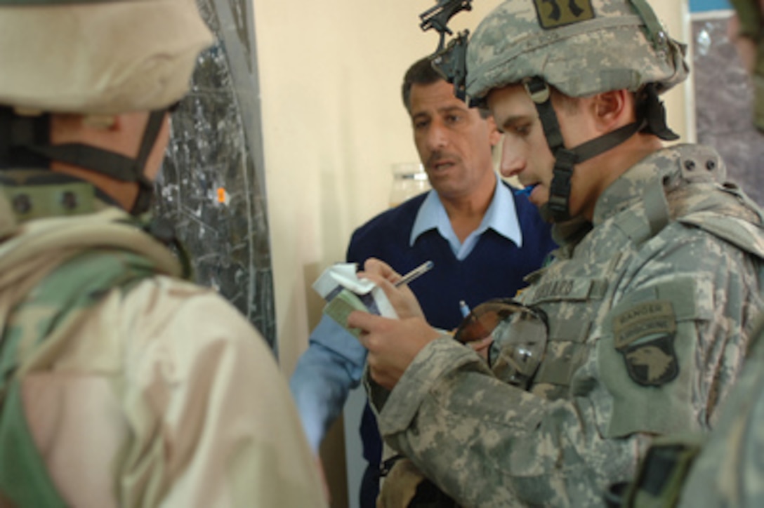 U.S. Army 2nd Lt. Patrick Vardaro (right) takes notes on the location of a bomb found by Iraqi police in Bayji, Iraq, on March 20, 2006. Vardaro is the platoon leader with 3rd Platoon, Bravo Company, 1st Battalion, 187th Infantry Regiment, 101st Airborne Division. 