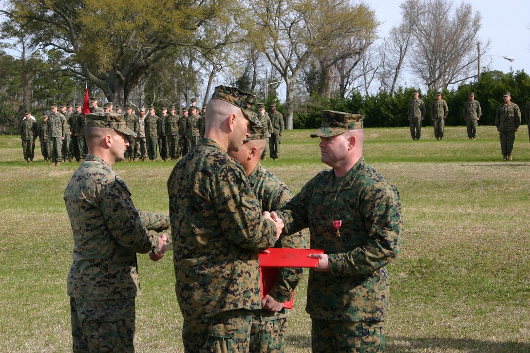 Gunnery Sgt. Mark R. Wynn (right), Force Protection Chief, Charlie Company, 8th Communication Battalion, receives his citation from Lt. Col. Michael M. Sweeney, commanding officer, 8th Comm. Bn., during a Bronze Star ceremony March 23. Wynn earned the award for directing over 70 convoys and his ability to effectively coordinate and influence multiple tasks simulatenously helped spearhead the movement of the battalion?s assets to Camp Fallujah to Al Taqaddum?s Marine Armor Installation Site (MAIS).