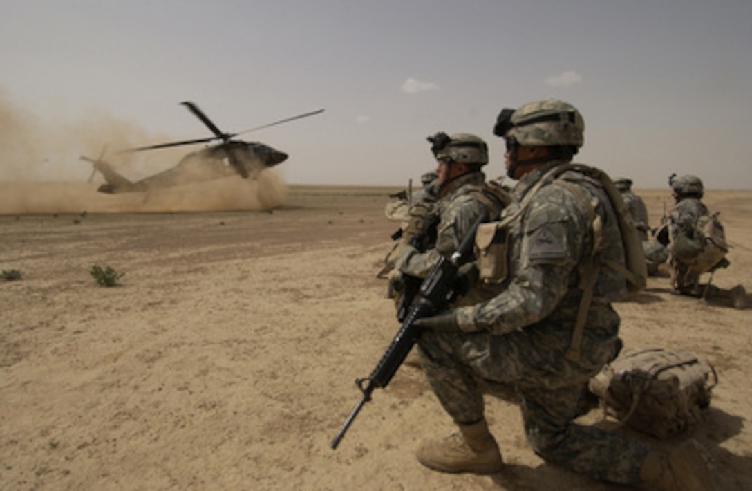 U.S. Army soldiers assigned to the 1st Brigade, 1st Armored Division wait to board a UH-60 Black Hawk helicopter during an air assault mission in the Al Jazeera Desert, Iraq, on March 22, 2006. 