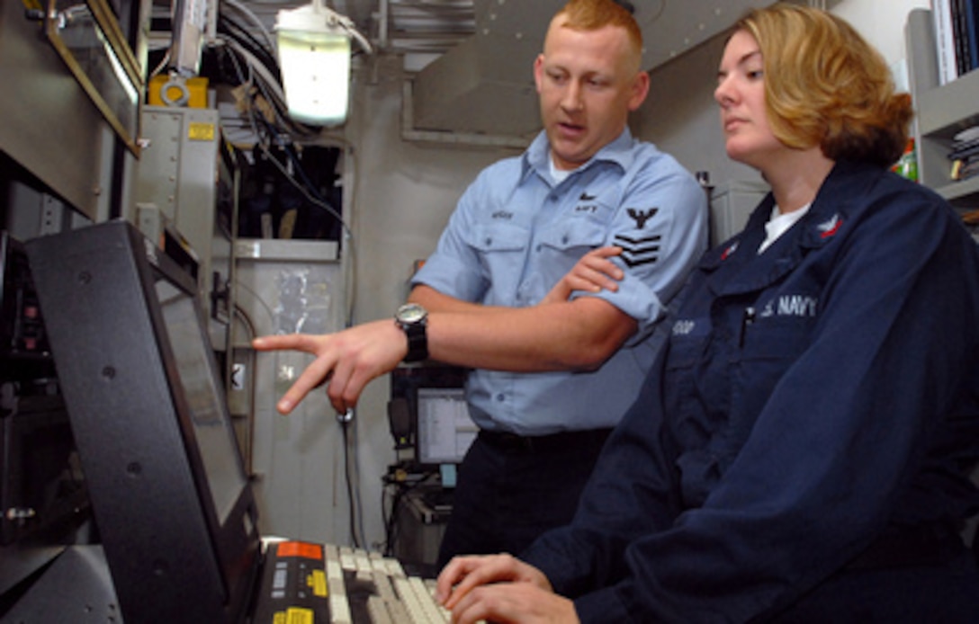 U.S. Navy Information Systems Technician 1st Class Chris Hedger (left) trains Information Systems Technician 2nd Class Susan Hood on the use of the information security system aboard the aircraft carrier USS Ronald Reagan (CVN 76) on March 22, 2006. 