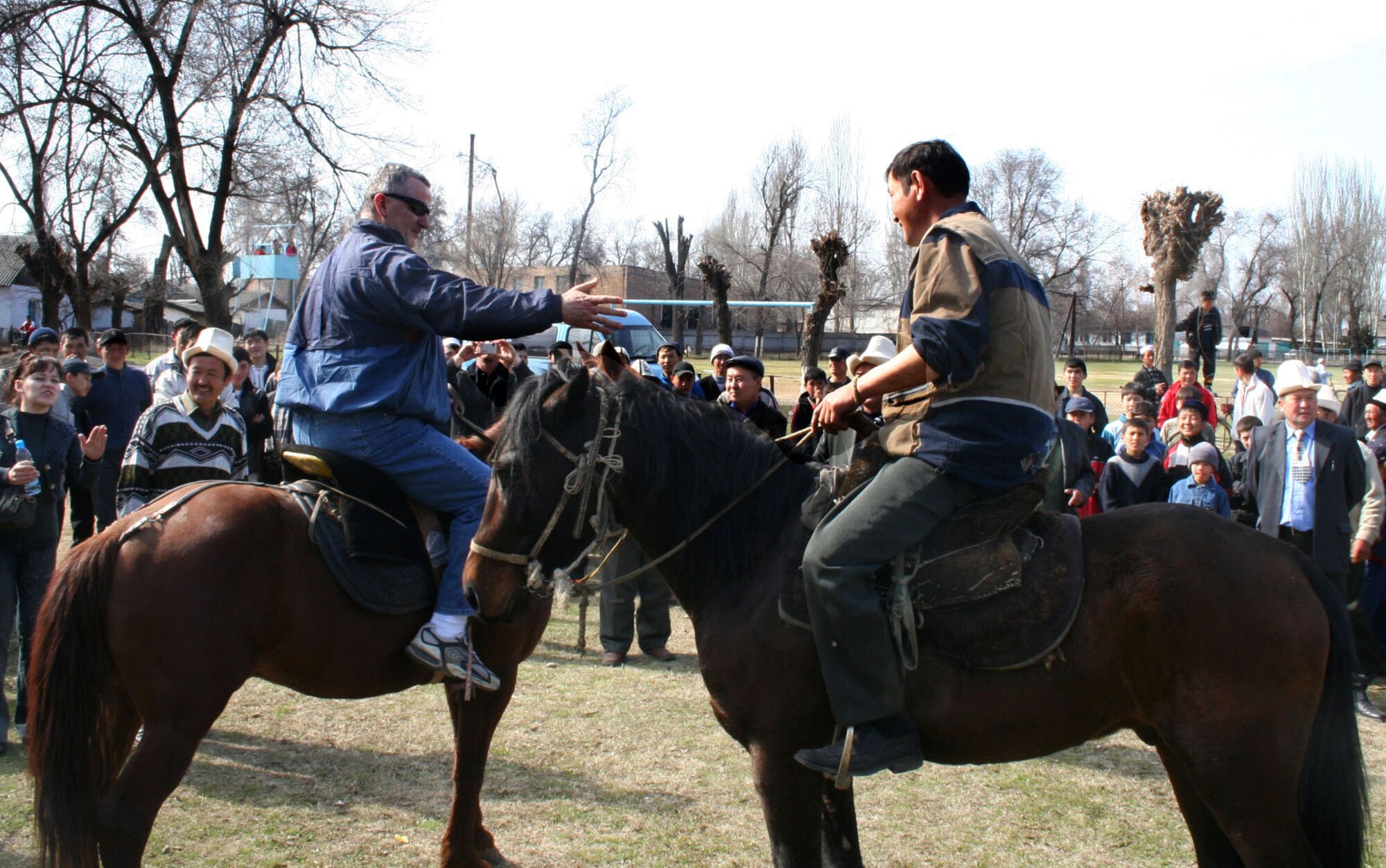 In Jani Jer, a village not far from Manas Air Base, Kyrgyzstan, Chaplain (Maj.) Mitchel Zygaldo reaches to shake hands with his competitor before horse wrestling, a Kyrgyz national sport. The chaplain and other 376th Air Expeditionary Wing leaders were invited by Mayor Batyrlan Kulov to join his village in celebrating Nooruz, a New Year celebration in some Muslim traditions. (U.S. Air Force photo/Staff Sgt. Lara Gale) 