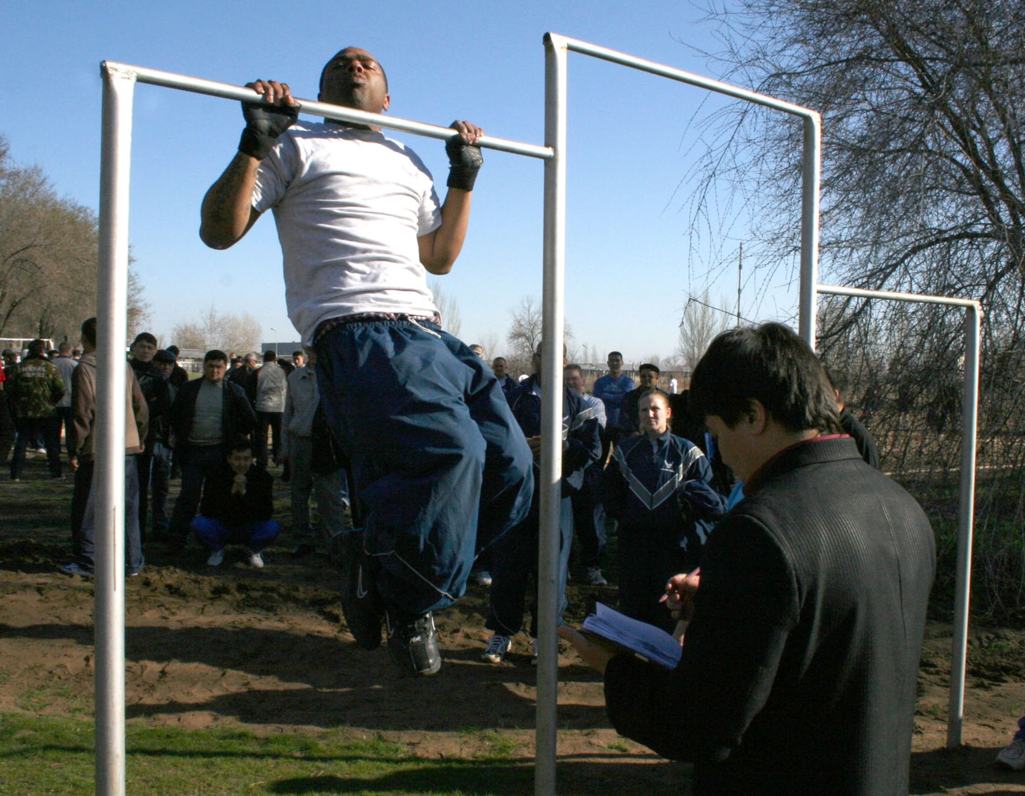 Senior Airman Darrell Davis pounds out 20 pull-ups in a Kyrgyz sports day honoring Revolution Day Thursday, March 23, 2006. Manas International Airport Secretary of Security, Mamyrov Nadybek, invited the Airmen to participate in the games as a mark of friendship and mutual respect. The day included races, tournaments and strength competitions, many unfamiliar to the American Airmen. Airman Davis is with the 376th Expeditionary Civil Engineer Squadron. (U.S. Air Force photo/Staff Sgt. Lara Gale) 