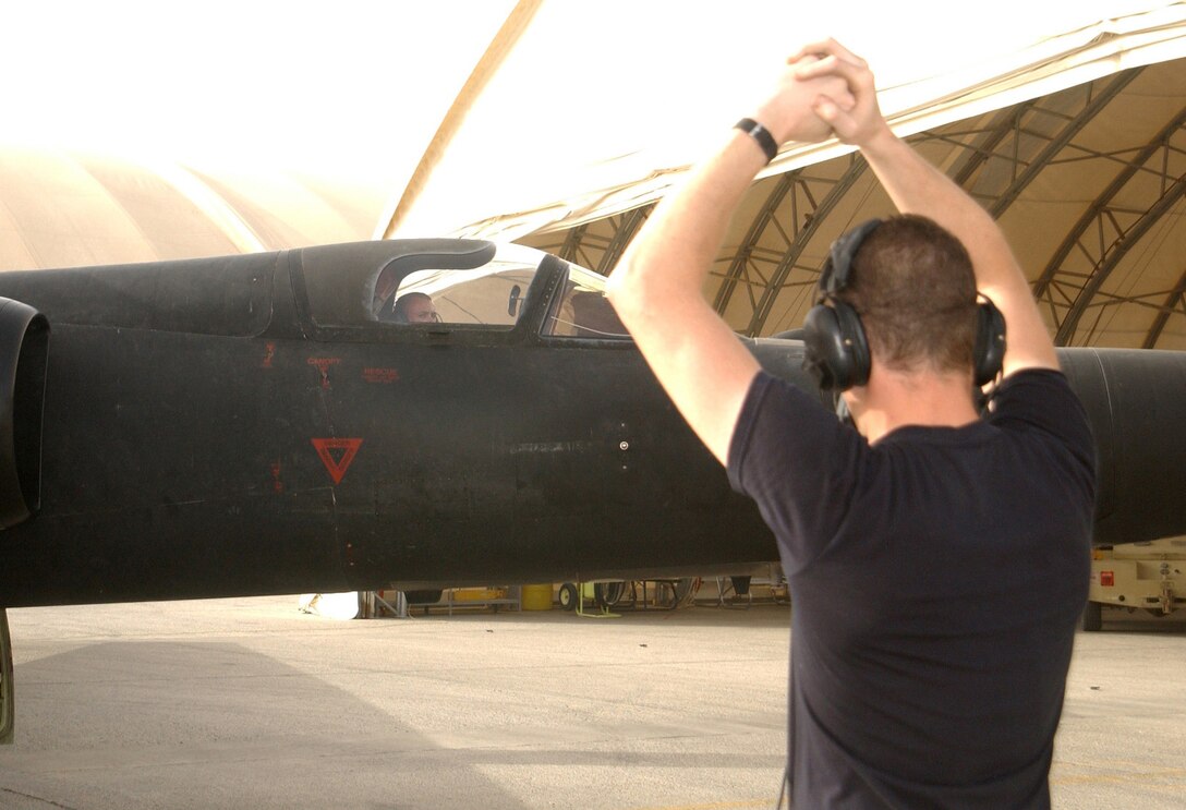 Airman 1st Class Justin Emmett gives the signal that air is being fed to start the turbine to Staff Sgt. Nathan Stillwell during a post-mission five-minute idle run test of a U-2 "Dragon Lady" at a forward-deployed location. Airman Emmett is with the 99th Aircraft Maintenance Unit, which has a streak of more than 155 consecutive launches without a maintenance-related cancel. Sergeant Stillwell and Airman Emmett are deployed from Beale Air Force Base, Calif. (U.S. Air Force photo/Tech. Sgt. Andrew Leonhard) 