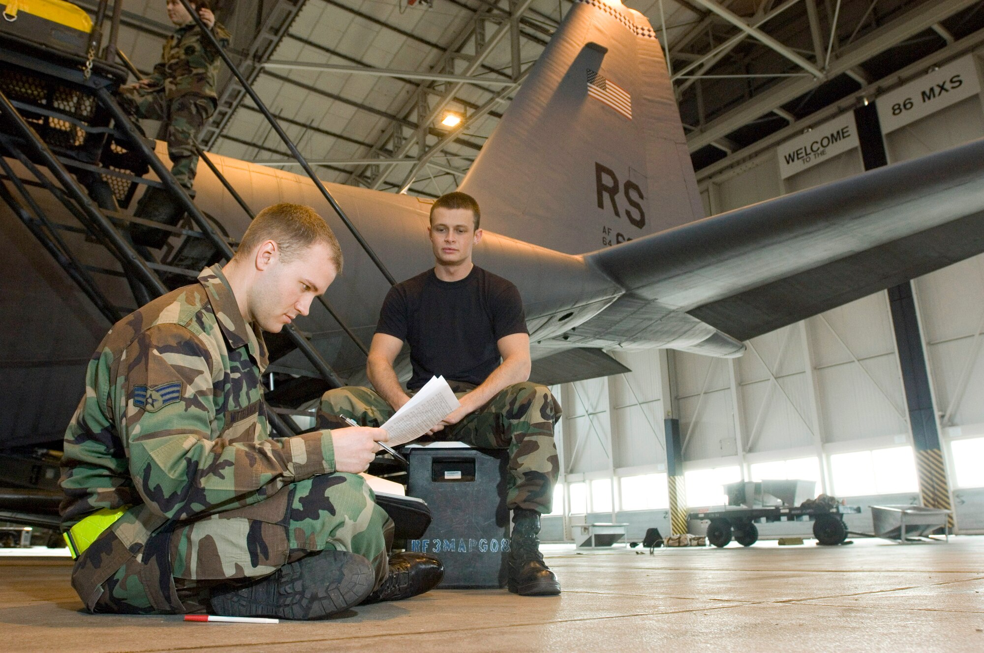 Senior Airman Nate Andrews waits as Senior Airman Brian Mittelbach reviews C-130 Hercules aircraft forms at Ramstein Air Base, Germany, on Monday, March 27, 2006. Airman Mittelbach, of Hamilton, Mass., and Airman Andrews, of Wilmington, N.C., are Hercules crew chiefs with the 86th Aircraft Maintenance Squadron. (U.S. Air Force photo/Master Sgt. John E. Lasky)