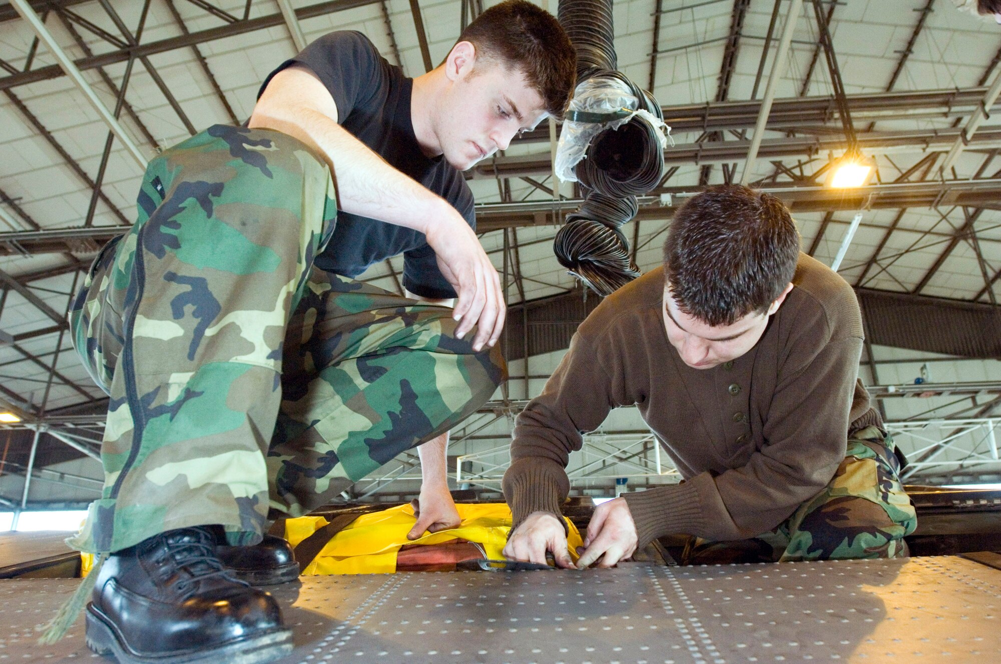 Airman 1st Class Beau Strausbaugh and Senior Airman Andrew Tishim, left to right, install a life raft into a C-130 Hercules at Ramstein Air Base, Germany, on Monday, March 27, 2006. The Airmen are Hercules crew chiefs with the 86th Aircraft Maintenance Squadron. (U.S. Air Force photo/Master Sgt. John E. Lasky)
