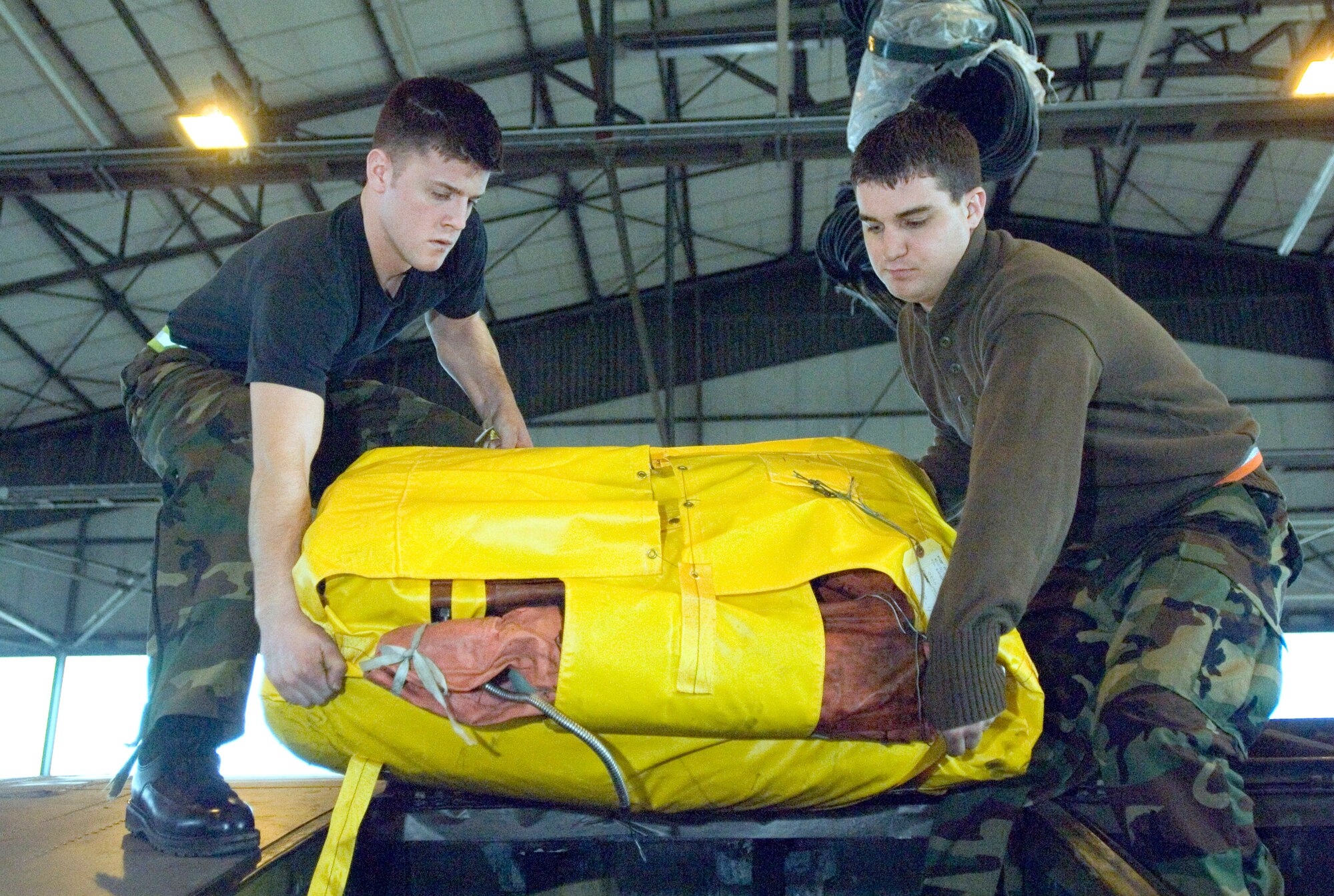 Airman 1st Class Beau Strausbaugh and Senior Airman Andrew Tishim, left to right, install a life raft into a C-130 Hercules at Ramstein Air Base, Germany, on Monday, March 27, 2006. The Airmen are Hercules crew chiefs with the 86th Aircraft Maintenance Squadron. (U.S. Air Force photo/Master Sgt. John E. Lasky)
