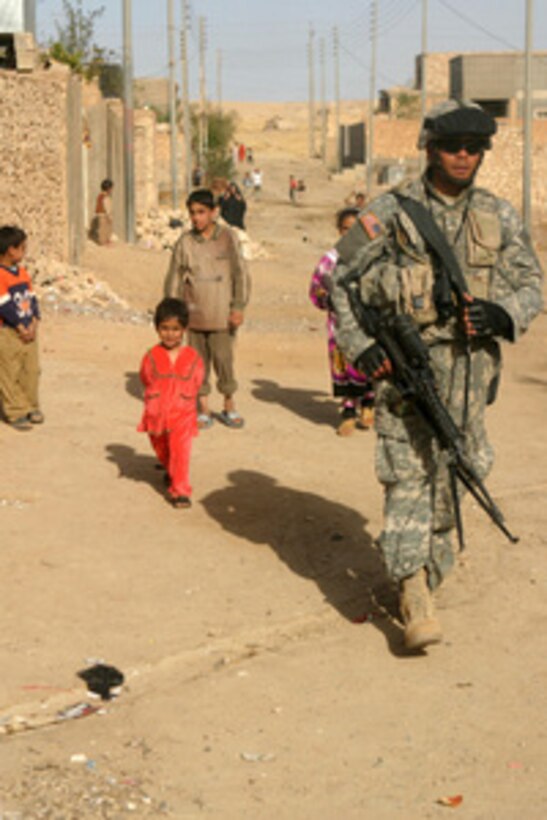 Iraqi children watch U.S. Army Pfc. Joel H. Timarong as he patrols through their neighborhood in the city of Hit, Iraq, on March 16, 2006. Timarong is attached to Alpha Company, 1st Battalion, 36th Infantry Regiment. 