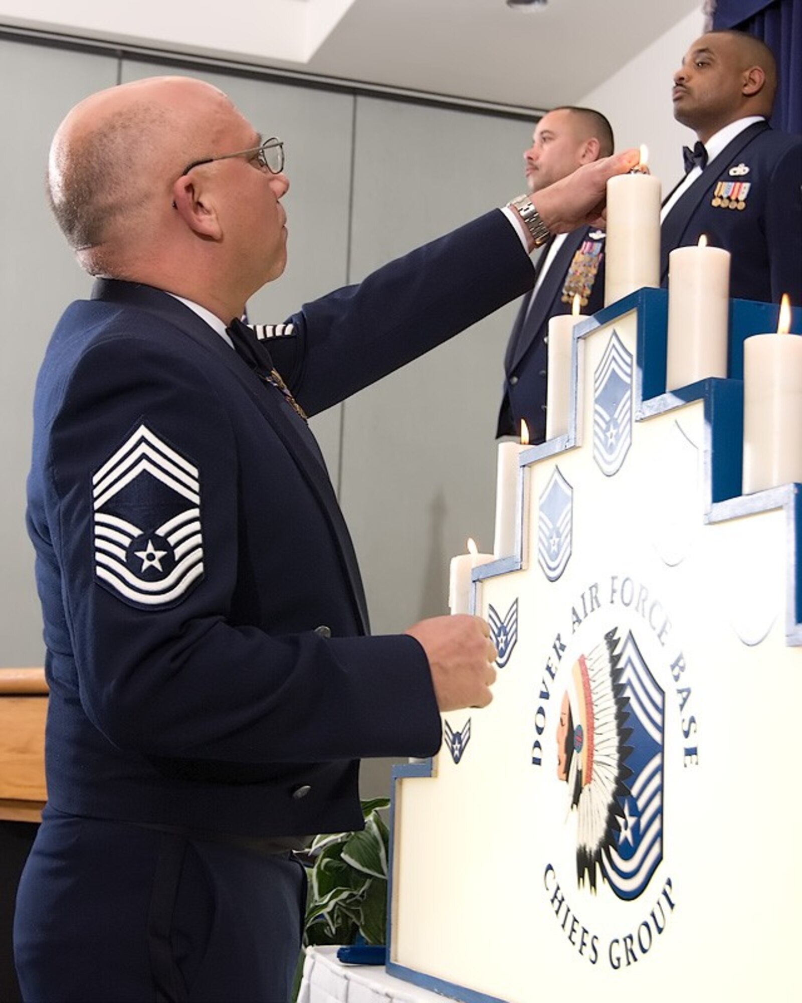 Chief Master Sgt. David Burke, 326th Airlift Squadron, lights the last candle in the candle lighting ceremony during the Chiefs' Induction Ceremony March 10 at The Landings Club. 