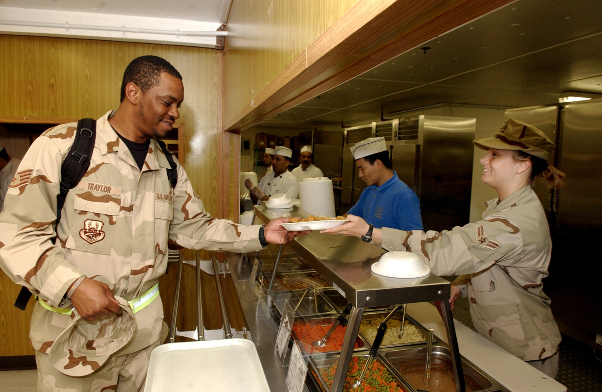 Airman 1st Class Carey Langworthy serves dinner to Staff Sgt. Prince Traylor at the Independence Dining Facility on Wednesday, March 22, 2006, at a forward-deployed location. Airman Langworthy is with the 379th Expeditionary Services Squadron and Sergeant Traylor is with the 379th Expeditionary Comptroller Squadron. (U.S. Air Force photo/Senior Airman Rachel Walters) 