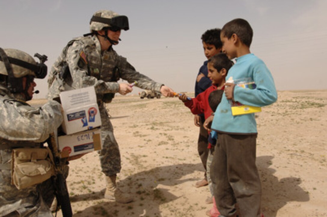 Army Maj. Jennifer Bailey hands out candy and school supplies to Iraqi children in a village near Contingency Operating Base Speicher, Iraq, on March 25, 2006. The goodwill visit helps build relationships between coalition forces and local Iraqi citizens. Bailey is from Bravo Company, 501st Special Troop Battalion, 101st Airborne Division. 