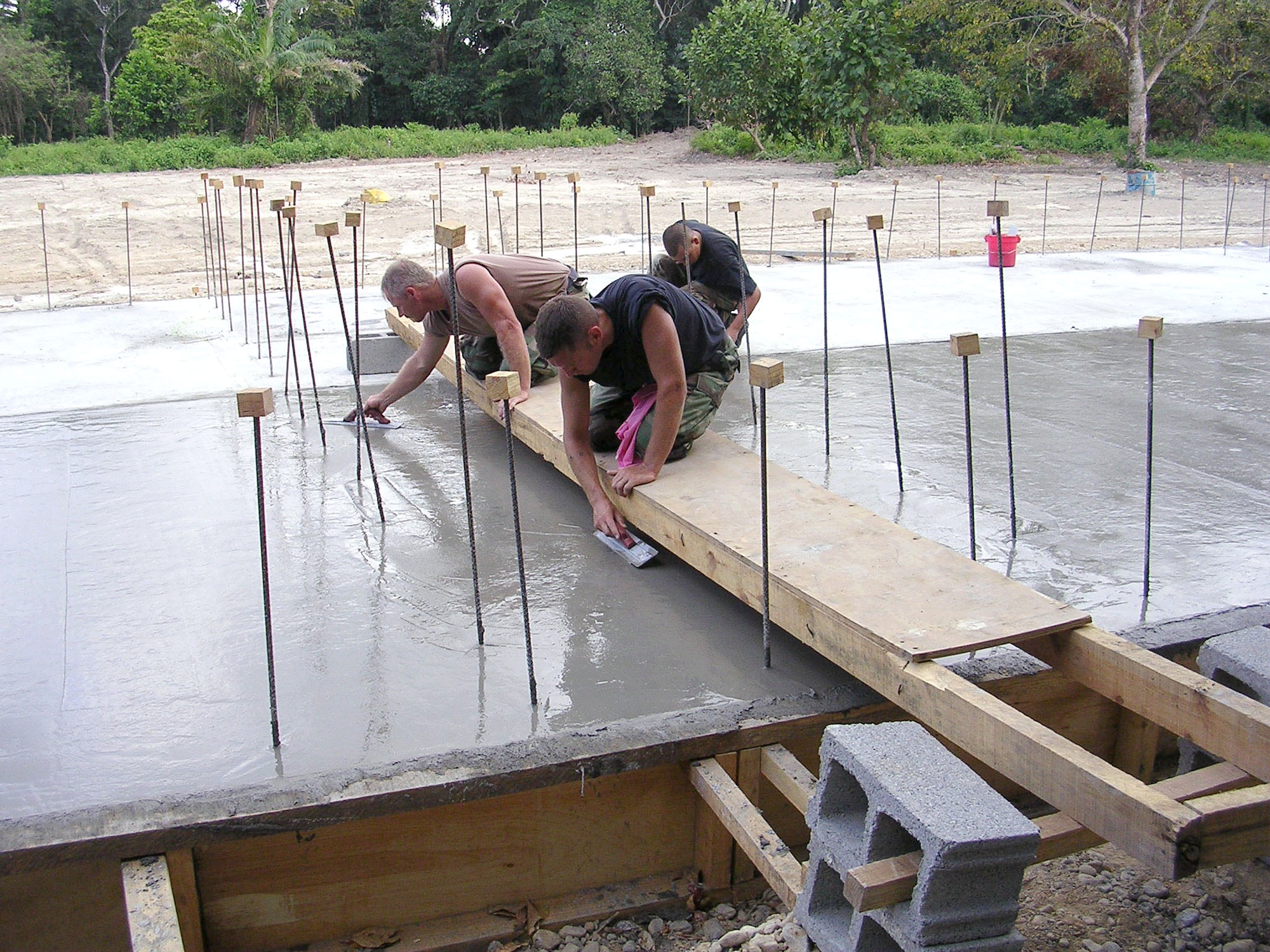 Senior Master Sgt. Mike Miller and Staff Sgt. Todd Benson use a bridge to reach areas of the El Cacao school foundation that needed to be smoothed while Senior Airman Julian Sisneros (background) smoothes the concrete along the edges. 17 Airmen are deployed from the 354th Civil Engineer Squadron at Eielson Air Force Base, Alaska, in support of New Horizons 2006-Honduras. (U.S. Air Force photo/2nd Lt. Sean Stapler)