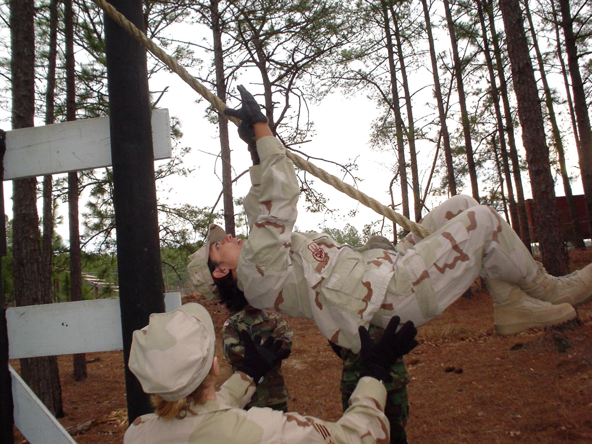 Capt. Birma Gonzalez climbs to the top of an obstacle on the leadership reaction course Monday, March 27, 2006, at Fort Bragg, N.C., while Senior Airman Melanie Weaver spots for safety.  Captain Gonzalez and Airman Weaver will deploy for a year with the Bagram Provincial Reconstruction Team in Afghanistan. Captain Gonzalez is from Barksdale Air Force Base, La., and Airman Weaver is from Andrews Air Force Base, Md. (U.S. Air Force photo/Capt. Mark D. Gibson) 
