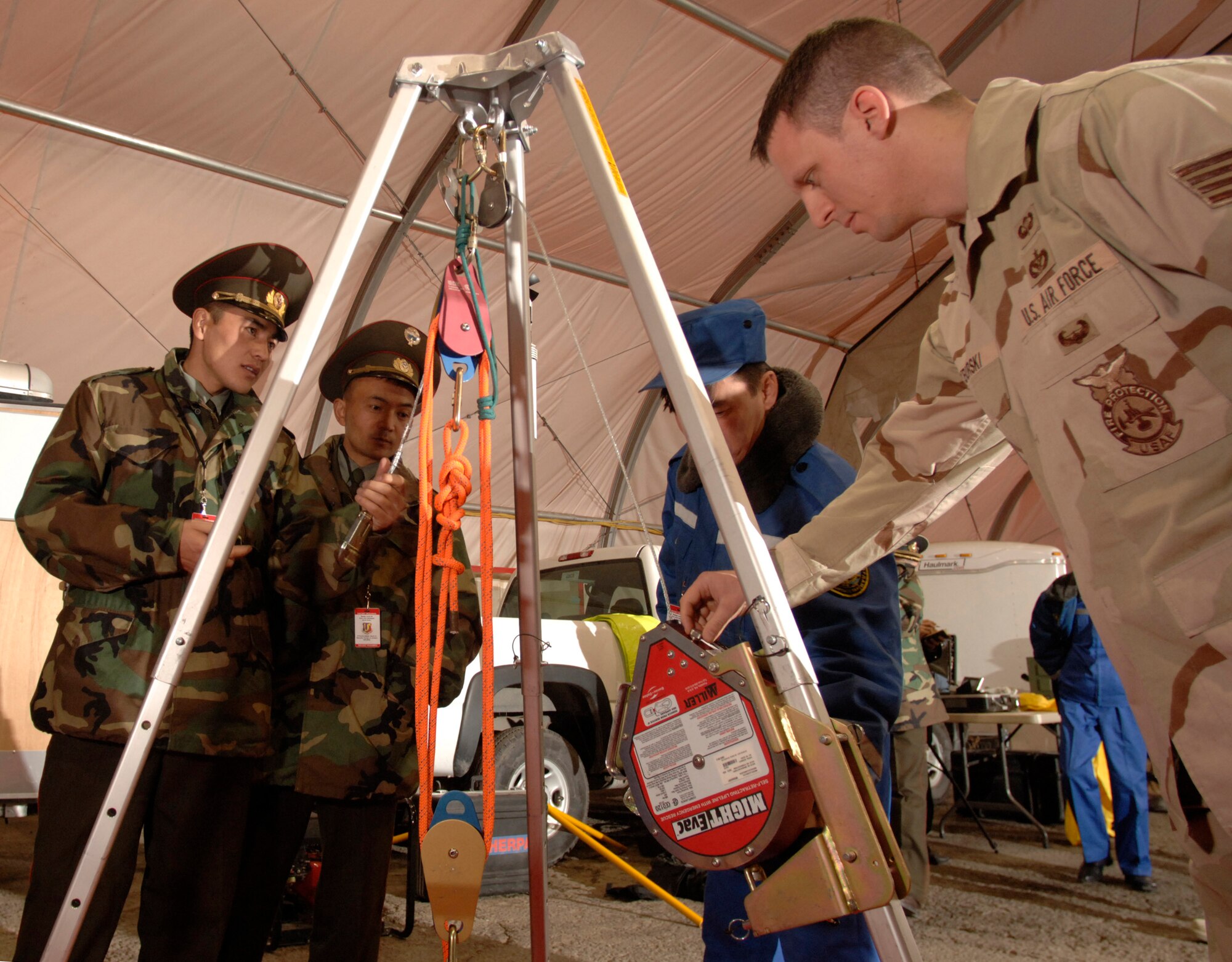 Staff Sgt. Michael Tyburski points out the features of a confined space tripod, harness and hoist during a visit by Kyrgyz emergency responders Saturday, March 18, 2006, at Manas Air Base, Kyrgyzstan. Sergeant Tyburski is deployed to the 376th Expeditionary Civil Engineer Squadron from the 366th CES at Mountain Home Air Force Base, Idaho.  (U.S. Air Force photo/Master Sgt. Lance Cheung)