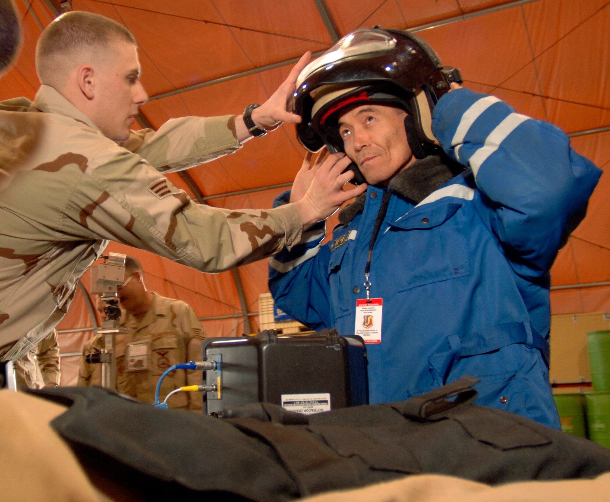 Senior Airman Robin Cunningham assists Stalbek Nurmanbetov with his bomb suit helmet during a visit by Kyrgyz emergency responders Saturday, March 18, 2006, at Manas Air Base, Kyrgyzstan. Airman Cunningham, an explosive ordnance disposal specialist, is deployed to the 376th Expeditionary Civil Engineer Squadron from the 509th CES at Whiteman Air Force Base, Mo. (U.S. Air Force photo/Master Sgt. Lance Cheung)
