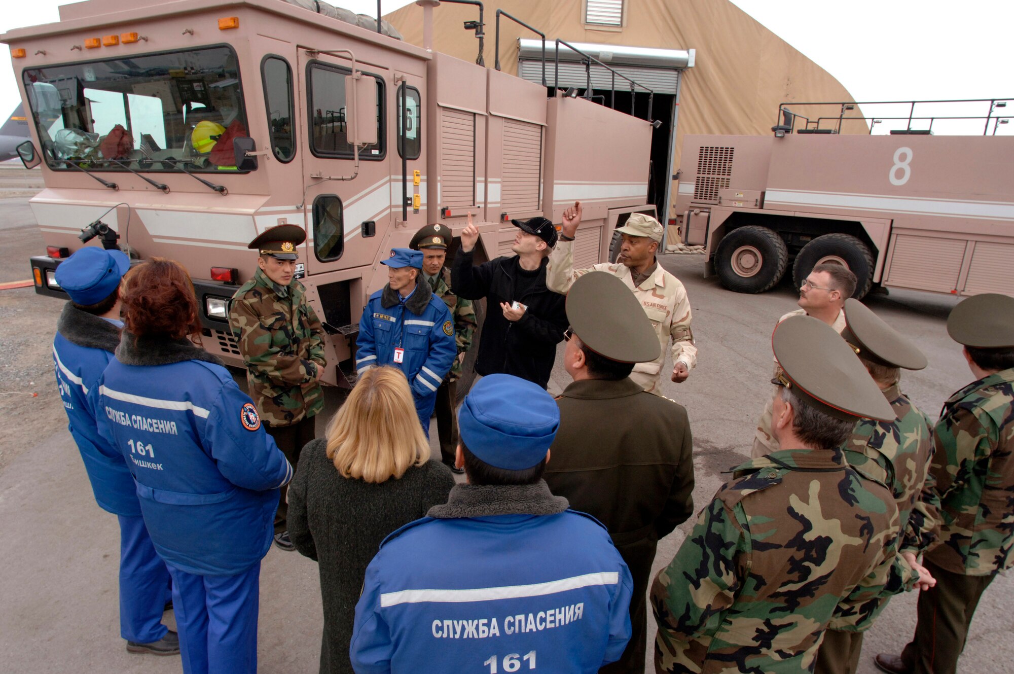 Alex Podkopayev (black cap) interprets as Senior Master Sgt. Gerald Johnson describes the features and capabilities of the TI-3000 major crash response vehicle during a visit by Bishkek emergency responders Saturday, March 18, 2006, at Manas Air Base, Kyrgyzstan. (U.S. Air Force photo/Master Sgt. Lance Cheung)