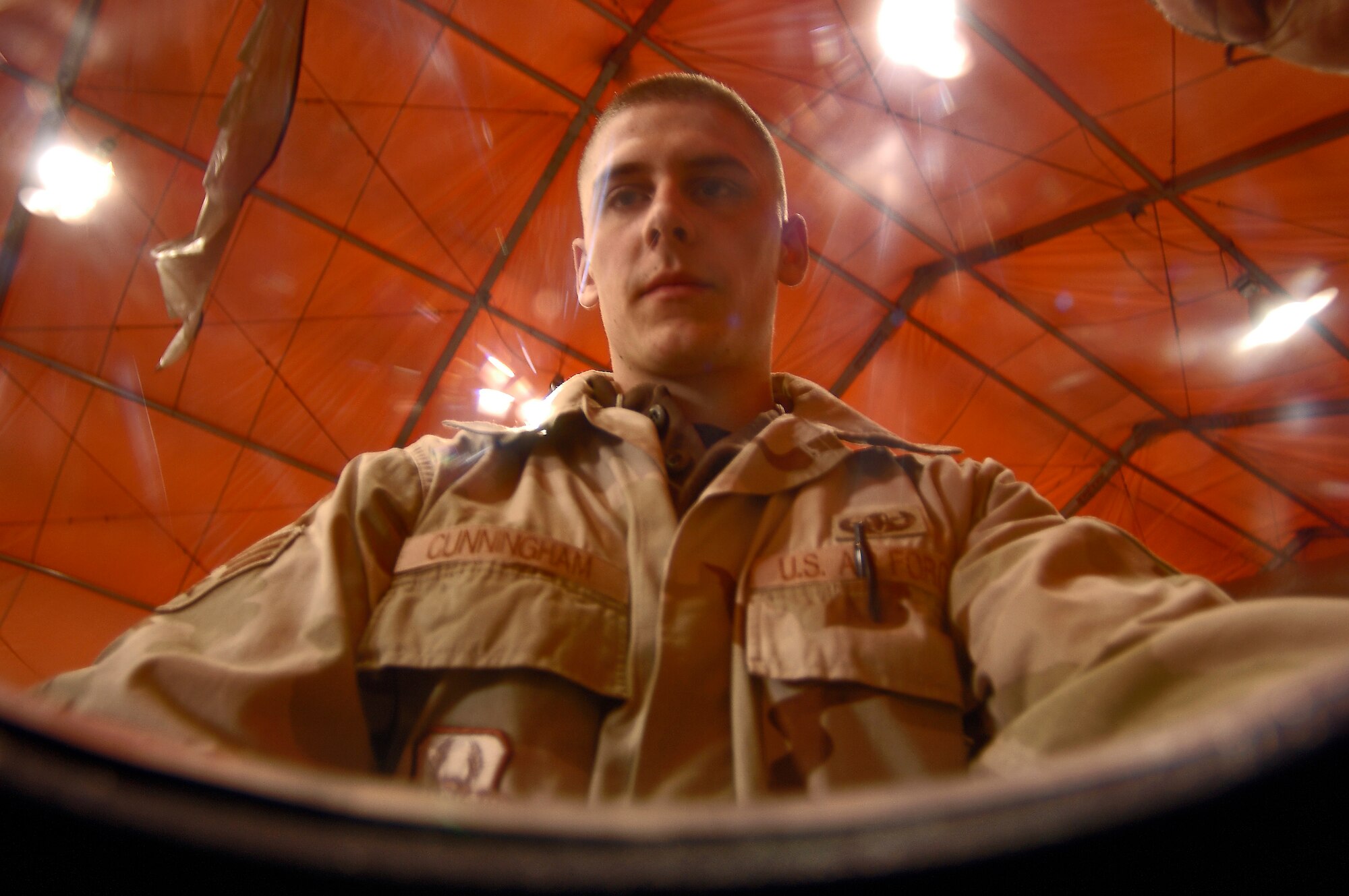 Senior Airman Robin Cunningham is seen from inside a bomb suit helmet as he prepares it for a visiting delegation of Bishkek emergency responders Saturday, March 18, 2006, at Manas Air Base, Kyrgyzstan. Airman Cunningham is deployed to the 376th Expeditionary Civil Engineer Squadron from the 509th CES at Whiteman Air Force Base, Mo.  (U.S. Air Force photo/Master Sgt. Lance Cheung)